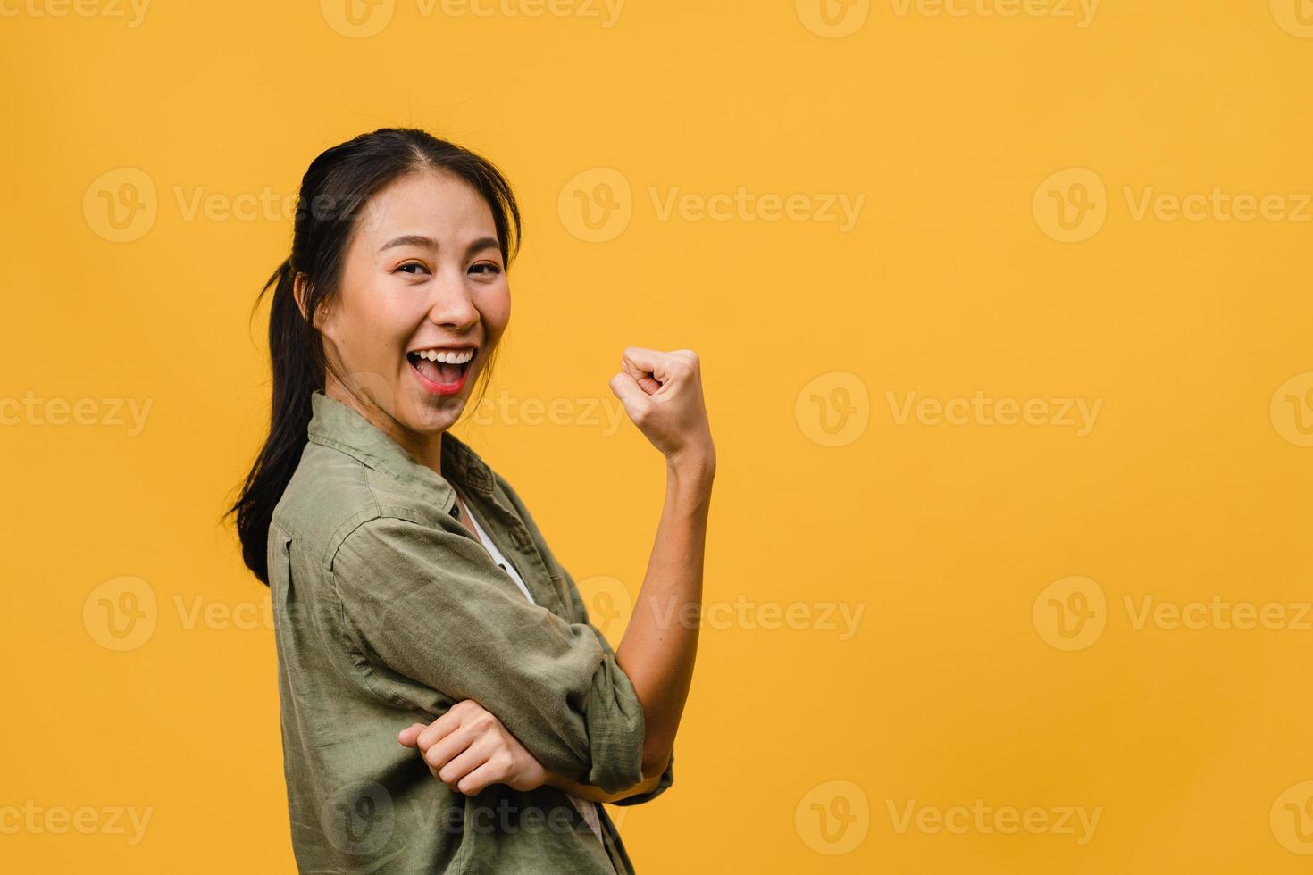 Young Asia lady with positive expression, joyful and exciting, dressed in casual cloth and look at camera over yellow background. Happy adorable glad woman rejoices success. Facial expression concept. photo