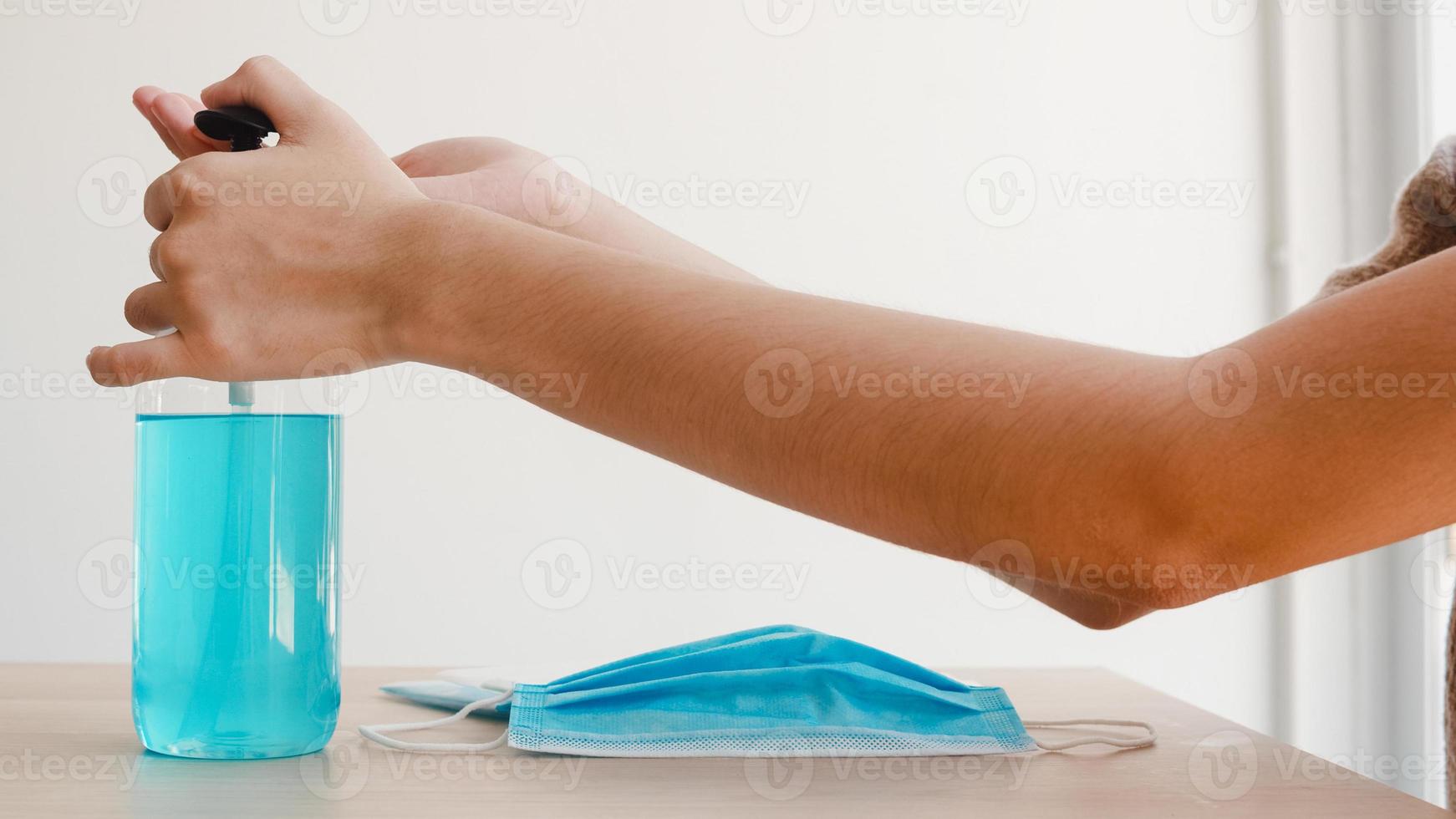 Asian woman using alcohol gel hand sanitizer wash hand before wear mask for protect coronavirus. Female push alcohol to clean for hygiene when social distancing stay at home and self quarantine time. photo