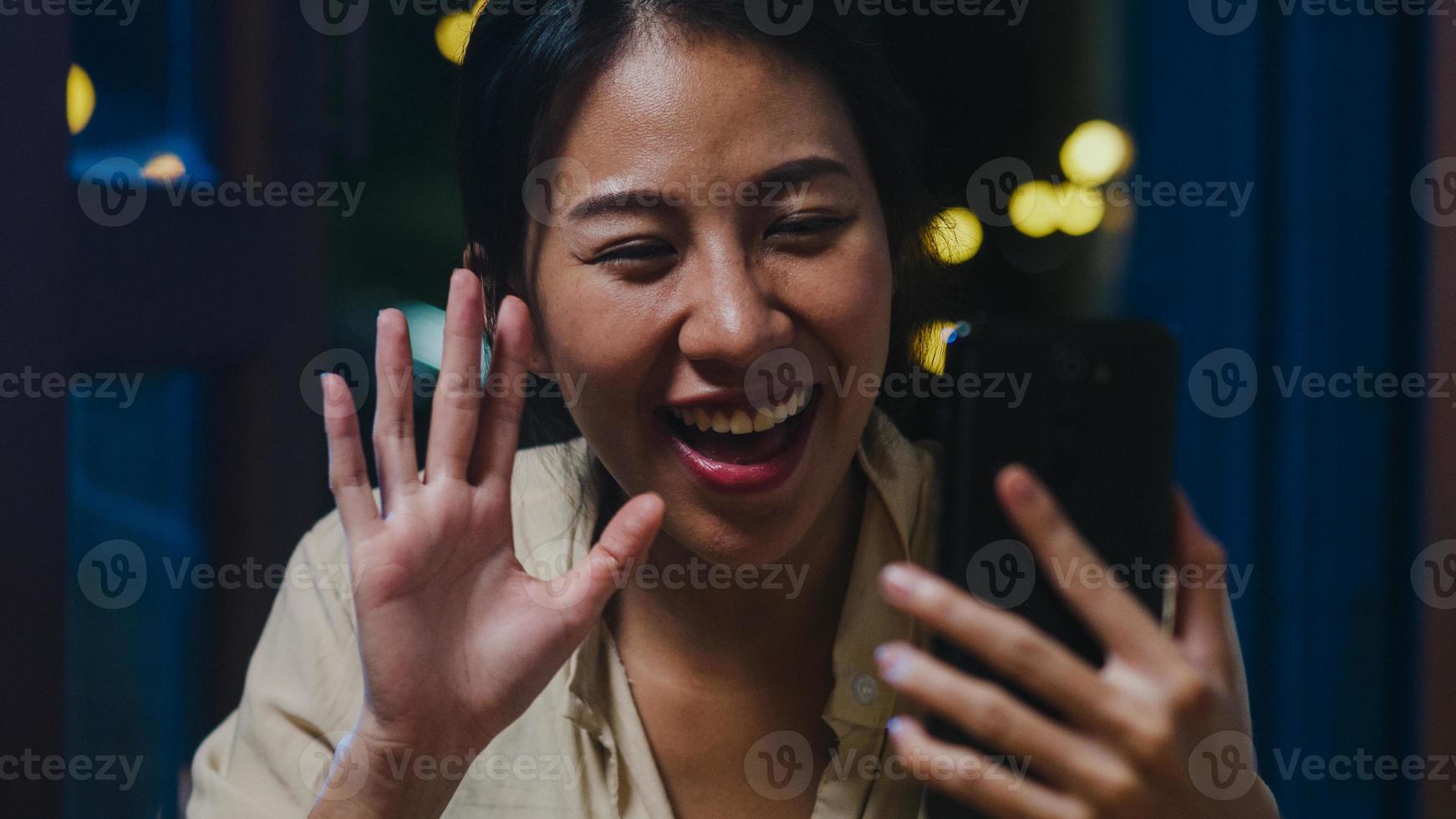 Young Asia lady drinking beer having fun happy moment night party New Year event online celebration via video call by phone at home at night. Social distancing, quarantine for coronavirus prevention. photo