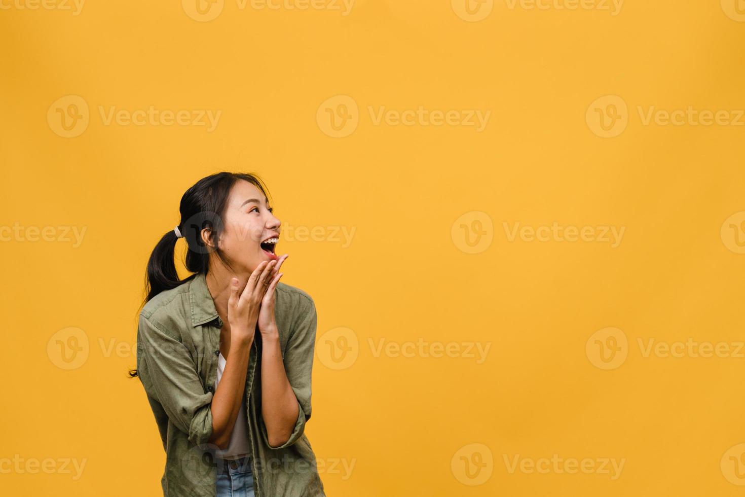 La joven dama de Asia siente felicidad con expresión positiva, alegre sorpresa funky, vestida con un paño casual aislado sobre fondo amarillo. feliz adorable mujer alegre se regocija con el éxito. expresión facial. foto