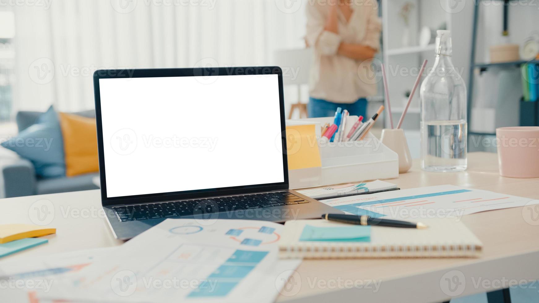 Computer laptop with blank white screen mock up display for advertising text on desk in living room at modern house. Chroma key technology, Marketing design concept. photo