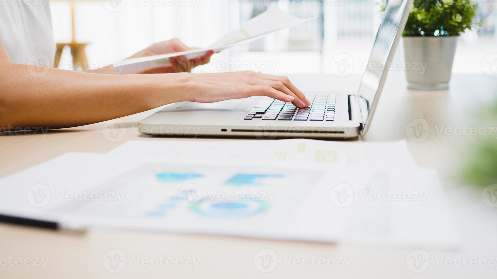 mujer de negocios asiática joven independiente ropa casual usando laptop trabajando en la sala de estar en casa. trabajo desde casa, trabajo a distancia, autoaislamiento, distanciamiento social, cuarentena para la prevención del coronavirus. foto