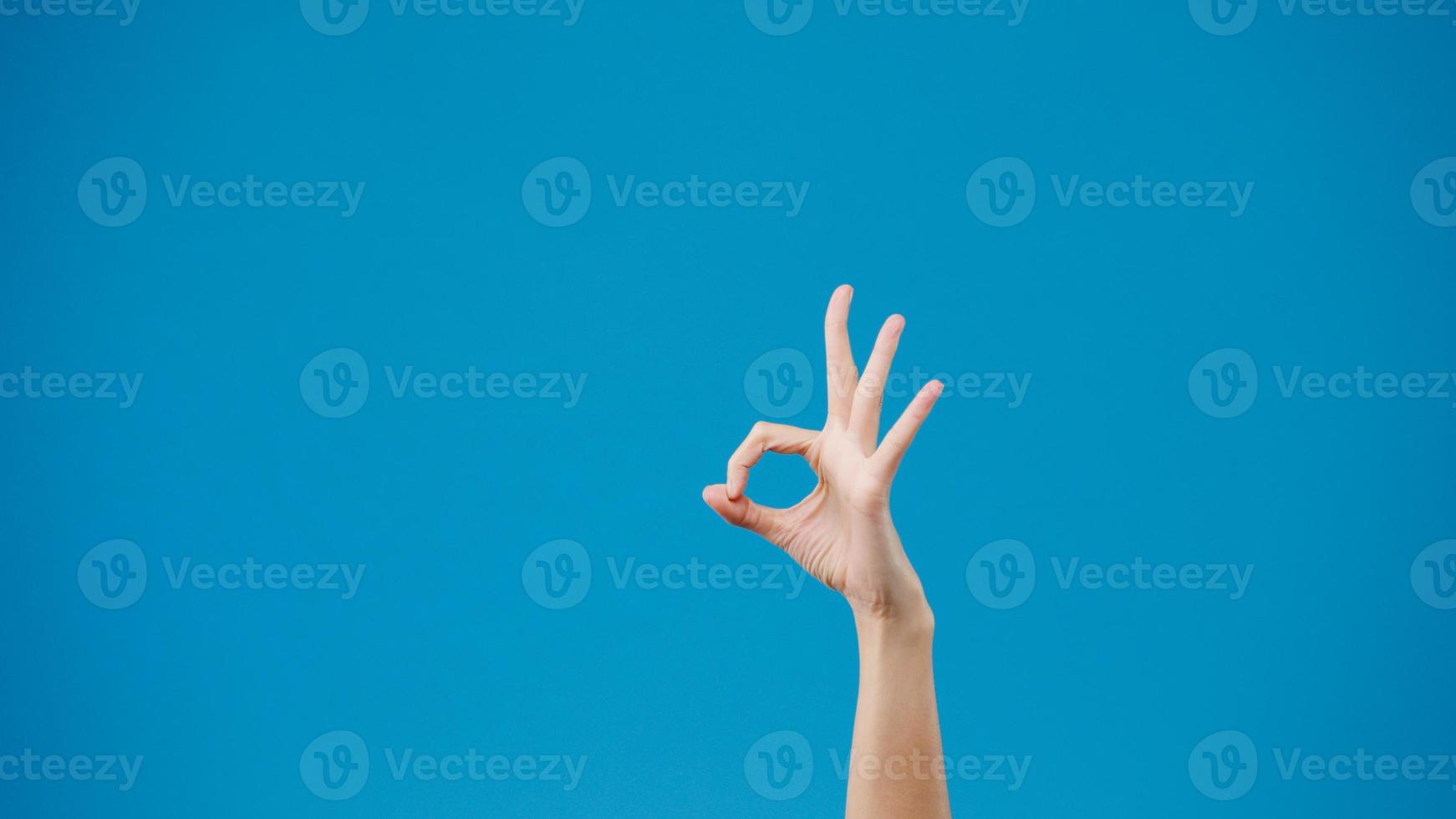 Young woman hand showing ok sign with fingers isolated over blue background in studio. Copy space for place a text, message for advertisement. Advertising area, mock up promotional content. Close up. photo