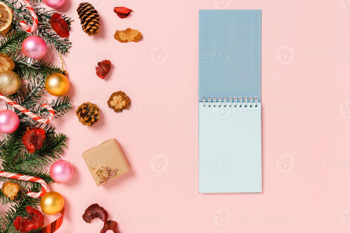 Minimal creative flat lay of winter christmas traditional composition and new year holiday season. Top view open mockup black notebook for text on pink background. Mock up and copy space photography. photo