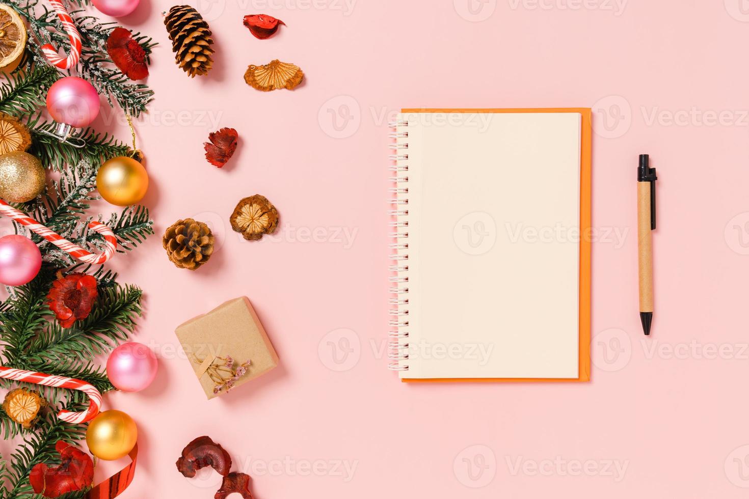 Minimal creative flat lay of winter christmas traditional composition and new year holiday season. Top view open mockup black notebook for text on pink background. Mock up and copy space photography. photo