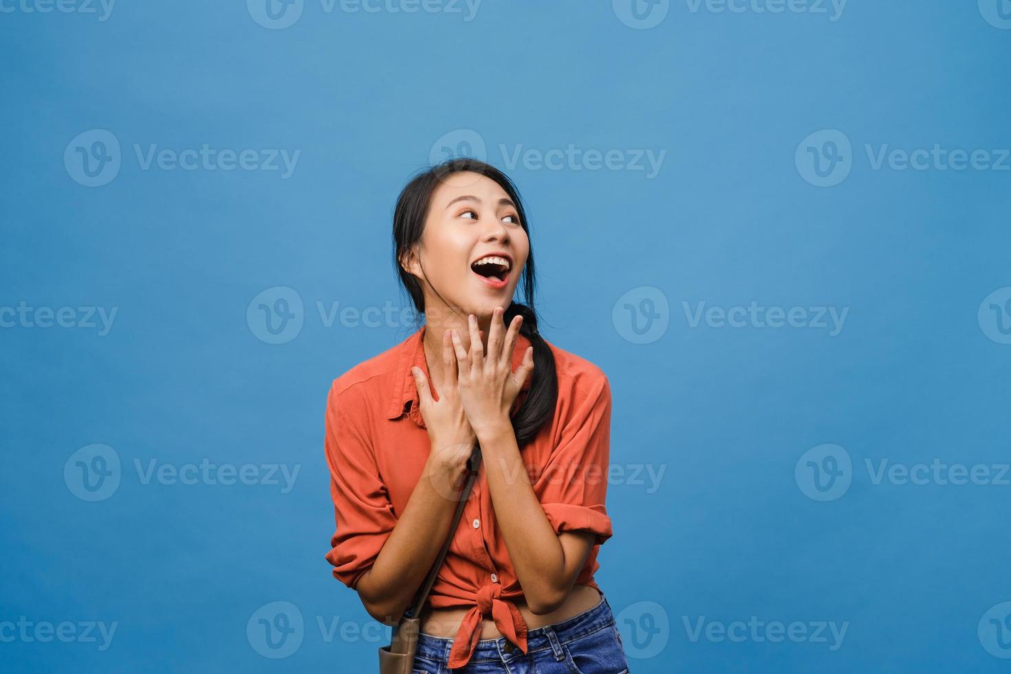 La joven dama de Asia siente felicidad con expresión positiva, alegre sorpresa funky, vestida con un paño informal aislado sobre fondo azul. feliz adorable mujer alegre se regocija con el éxito. expresión facial. foto