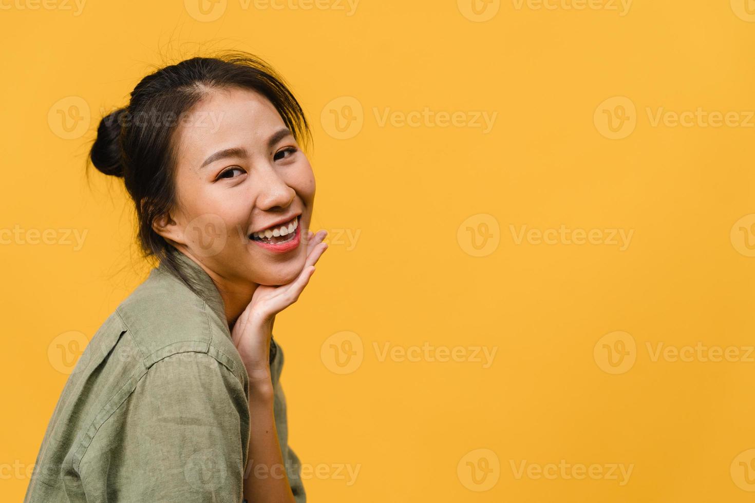 Young Asia lady with positive expression, smile broadly, dressed in casual clothing and looking at camera over yellow background. Happy adorable glad woman rejoices success. Facial expression concept. photo