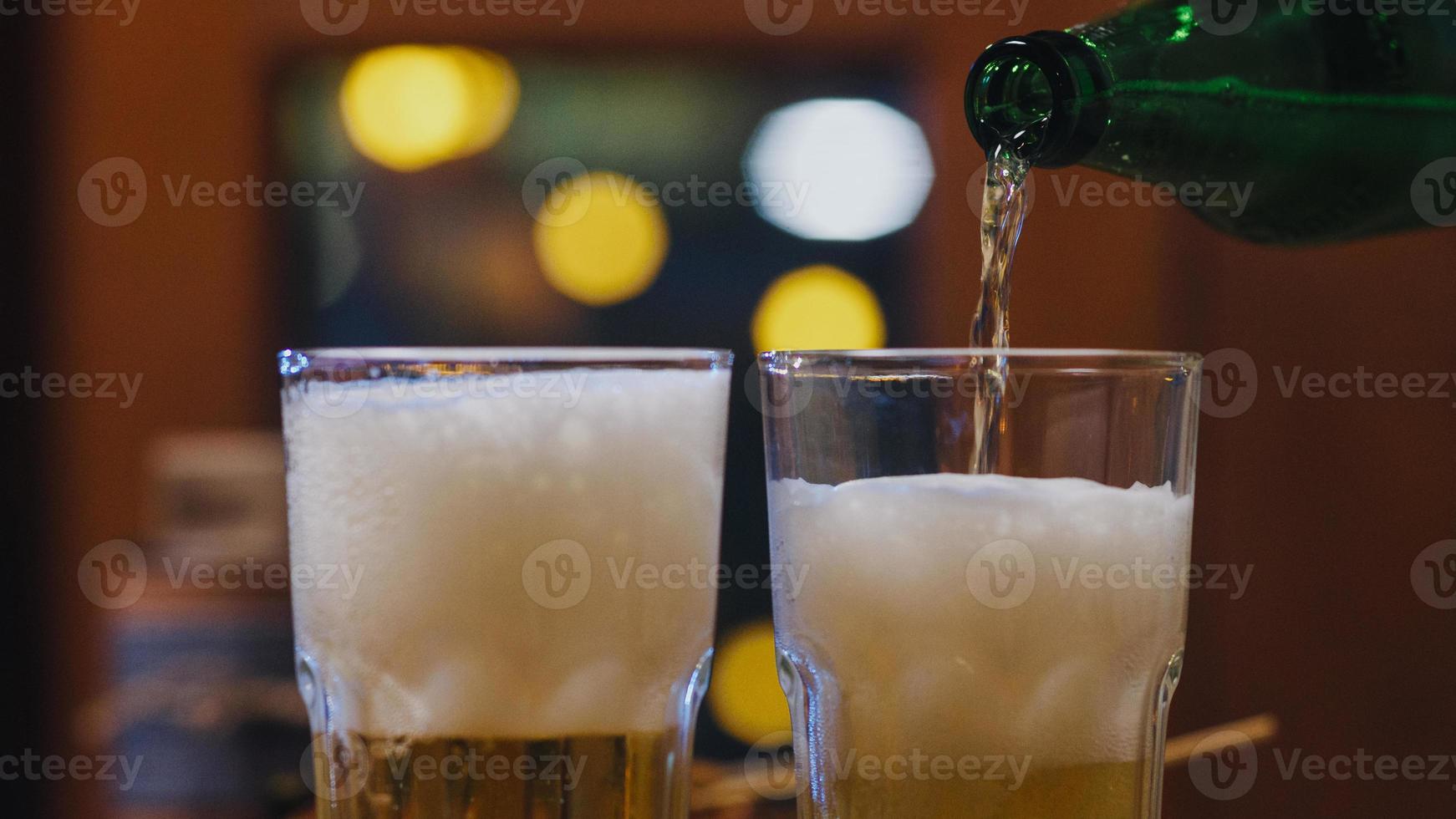 Group of happy tourist young Asia friends pouting craft beer into glass and having hangout party in night club at The Khao San Road. Traveler backpacker Asia people travel in Bangkok, Thailand. photo