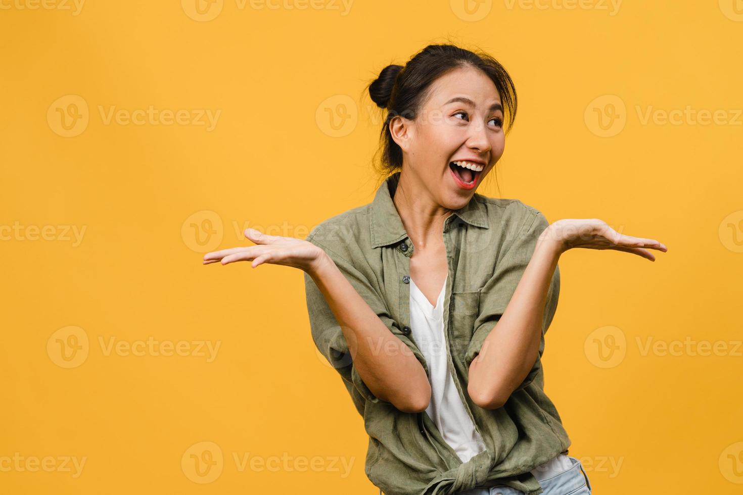 La joven dama de Asia siente felicidad con expresión positiva, alegre sorpresa funky, vestida con un paño casual aislado sobre fondo amarillo. feliz adorable mujer alegre se regocija con el éxito. expresión facial. foto