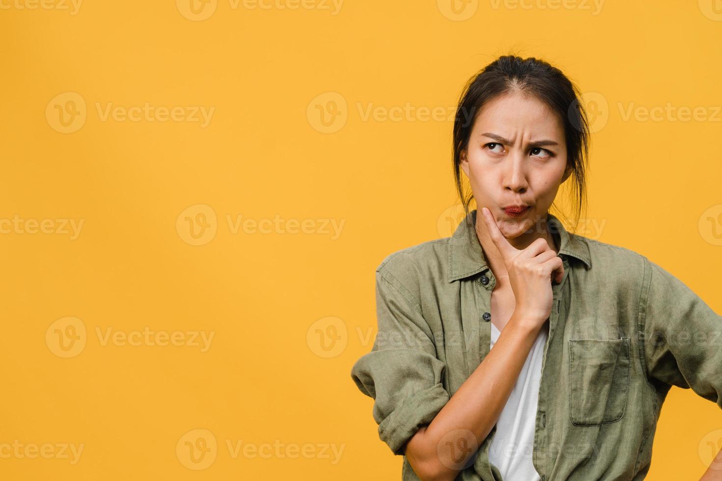 Retrato de joven asiática con expresión positiva, piensa en las próximas vacaciones, vestida con ropa casual sobre fondo amarillo con espacio de copia en blanco. feliz adorable mujer alegre se regocija con el éxito. foto