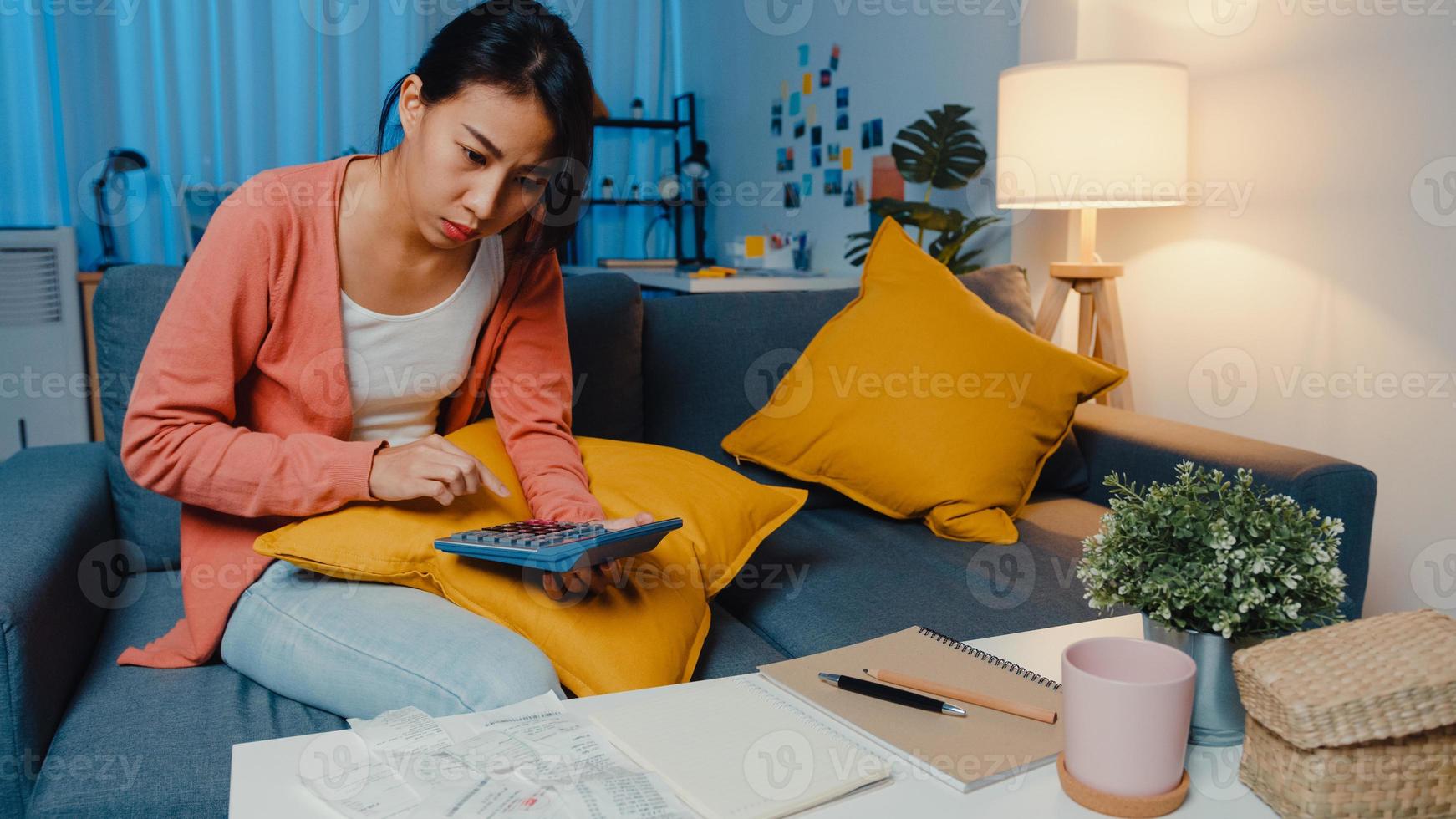 Asian lady feel stress and worried with bill and invoice credit card calculating loan on sofa at home. Home loan stress, Get loan no job,  Coronavirus hardship loans, Can't make loan payment concept. photo