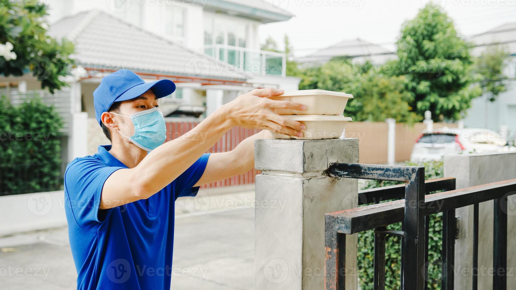 Young postal delivery courier man wear face mask handling food box for send to customer at house and Asian female receive delivered package outdoors. Lifestyle new normal after corona virus concept. photo