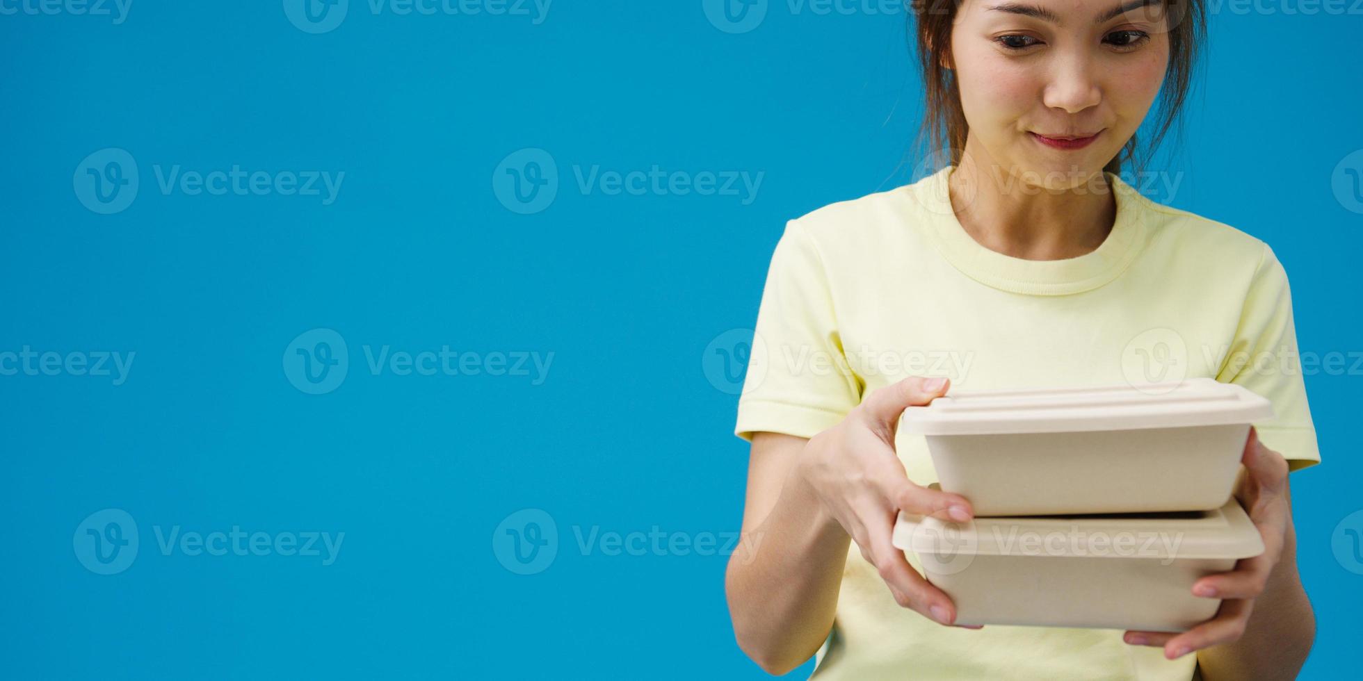 Young woman hand hold brown clear empty blank craft paper box food for takeaway over blue background. Copy space for place a text for advertisement. Advertising area, mock up promotional content. photo