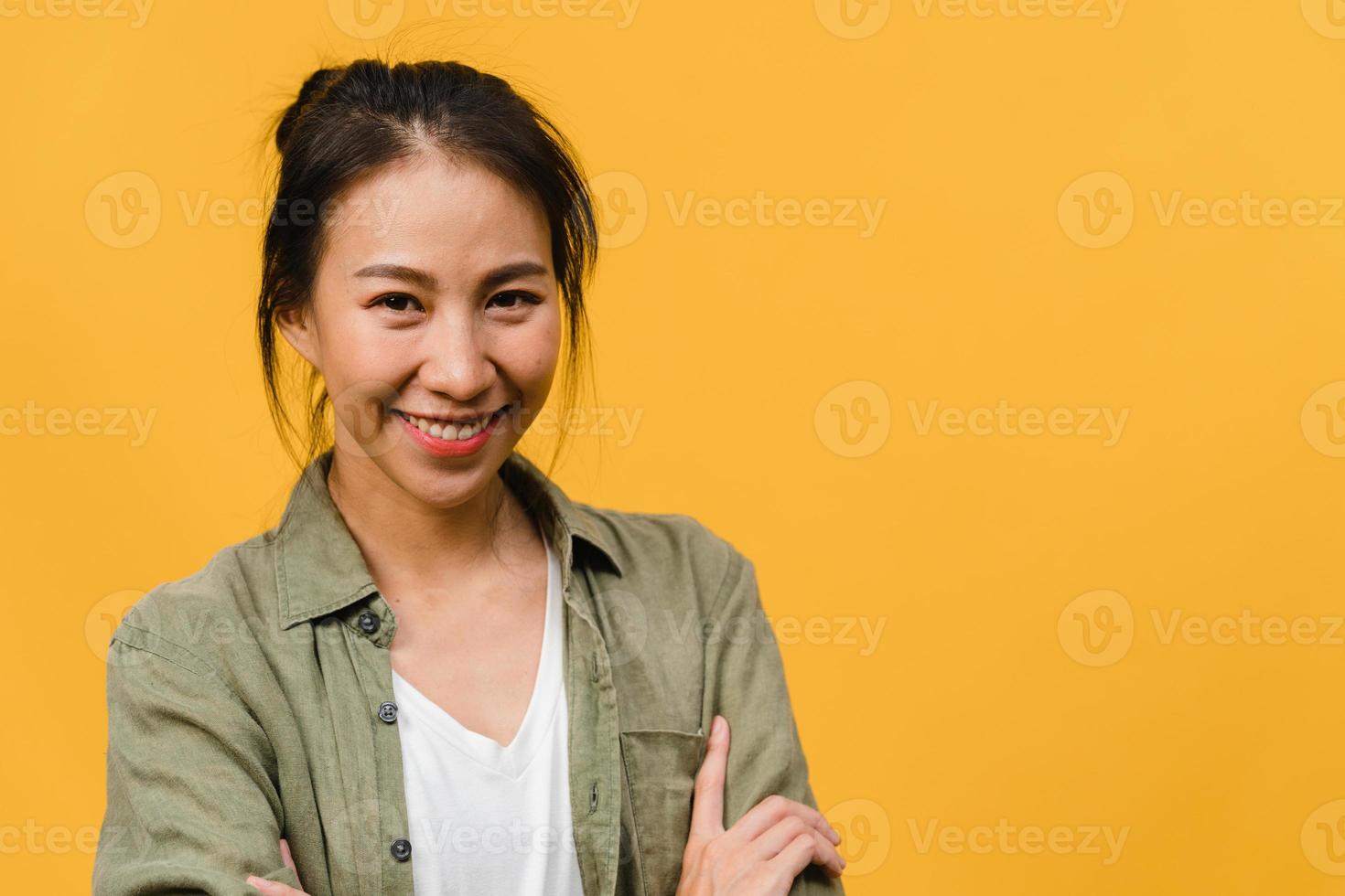Portrait of young Asia lady with positive expression, arms crossed, smile broadly, dressed in casual clothing and looking at camera over yellow background. Happy adorable glad woman rejoices success. photo