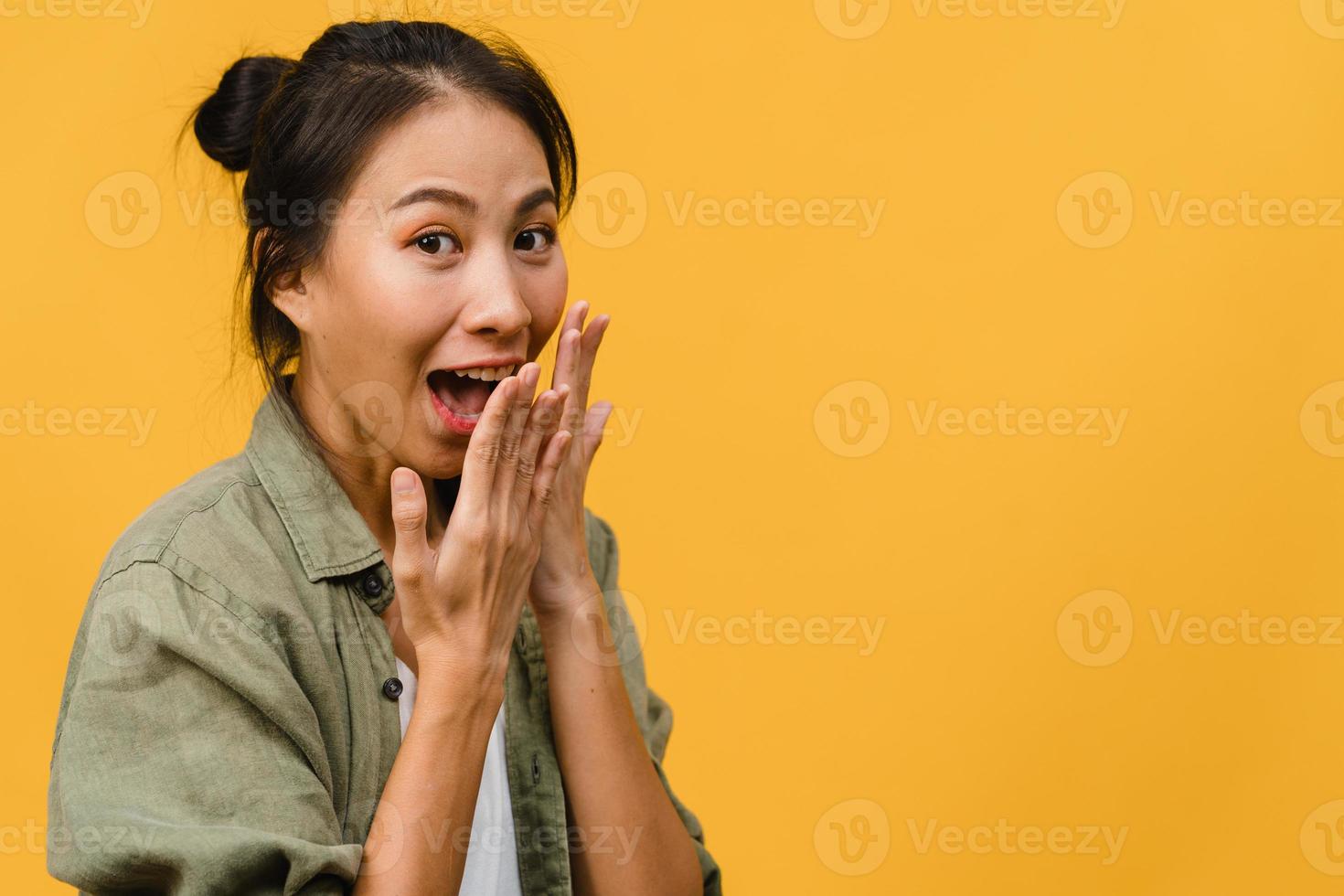 La joven asiática siente felicidad con expresión positiva, alegre sorpresa funky, vestida con ropa informal y mirando a cámara aislada sobre fondo amarillo. feliz adorable mujer alegre se regocija con el éxito. foto