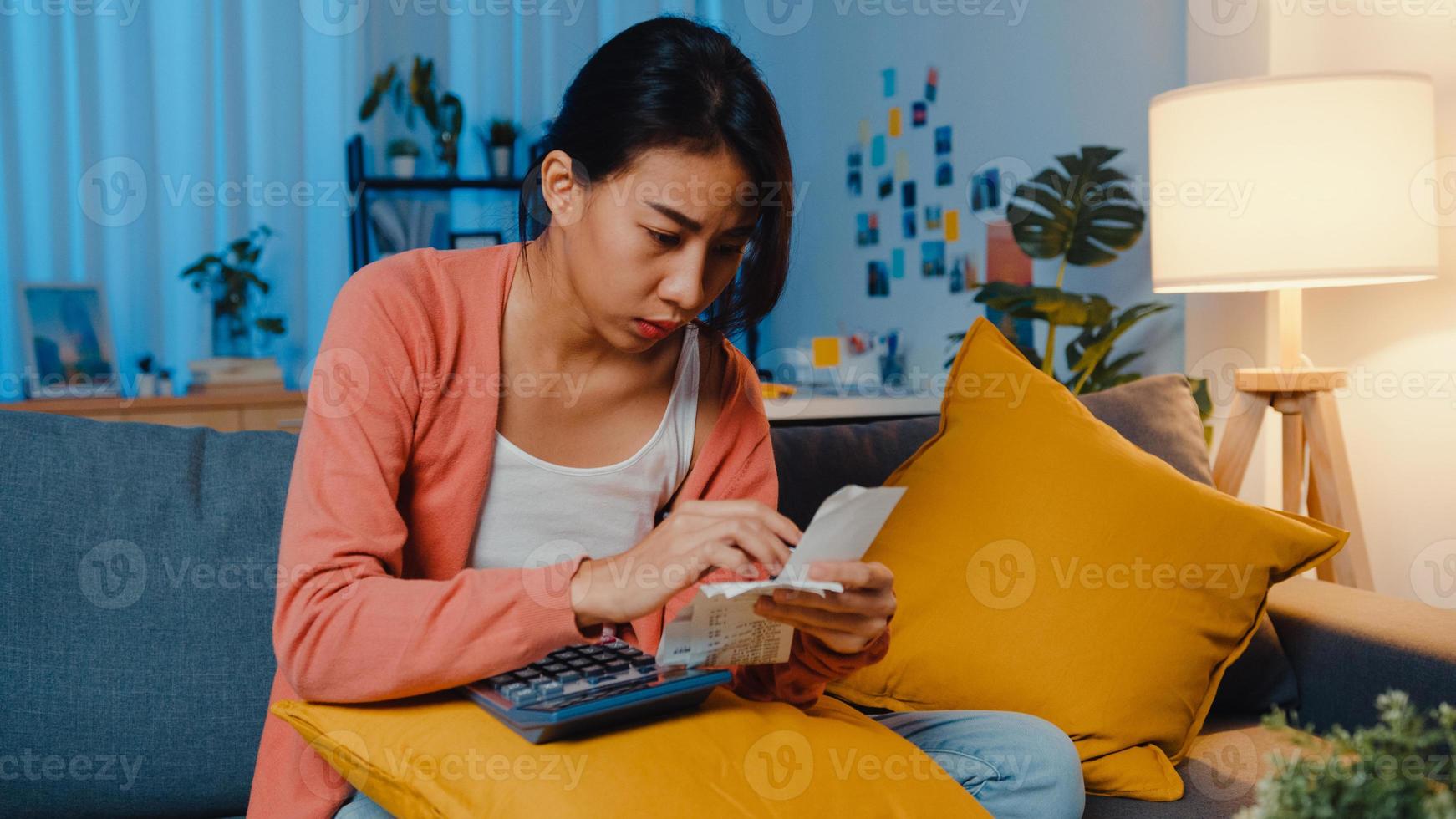 Asian lady feel stress and worried with bill and invoice credit card calculating loan on sofa at home. Home loan stress, Get loan no job,  Coronavirus hardship loans, Can't make loan payment concept. photo