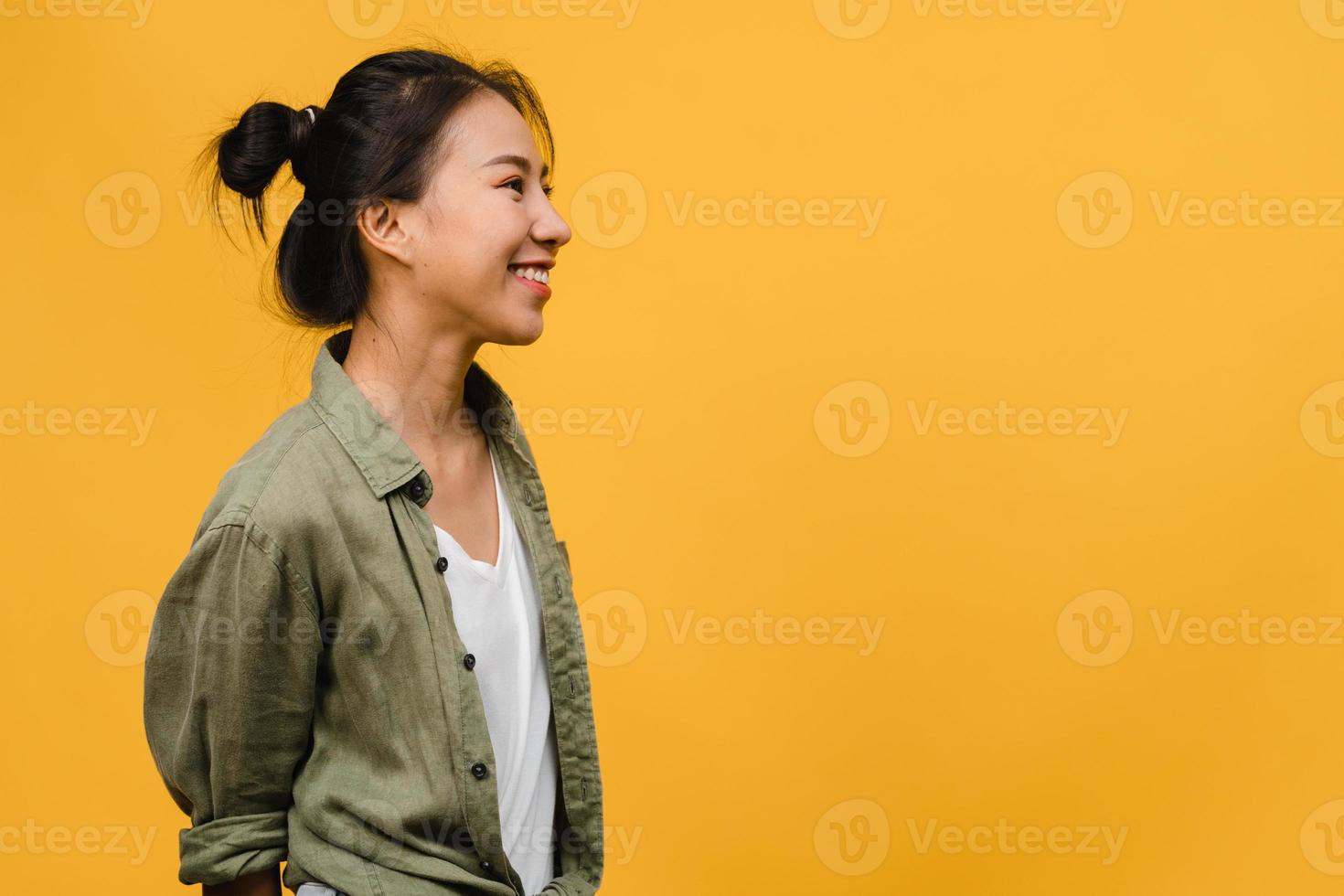 Portrait of young Asia lady with positive expression, smile broadly, dressed in casual clothing over yellow background. Happy adorable glad woman rejoices success. Facial expression concept. photo