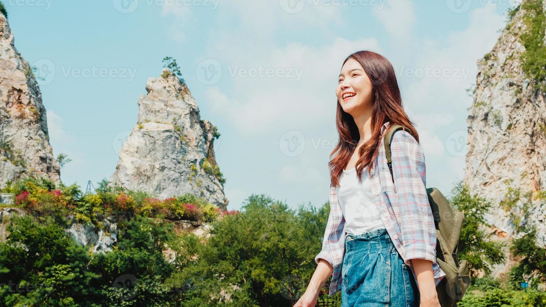 Cheerful young traveler Asian lady with backpack walking at the mountain lake. Korean teen girl enjoy her holidays adventure feeling happy freedom. Lifestyle travel and relax in free time concept. photo