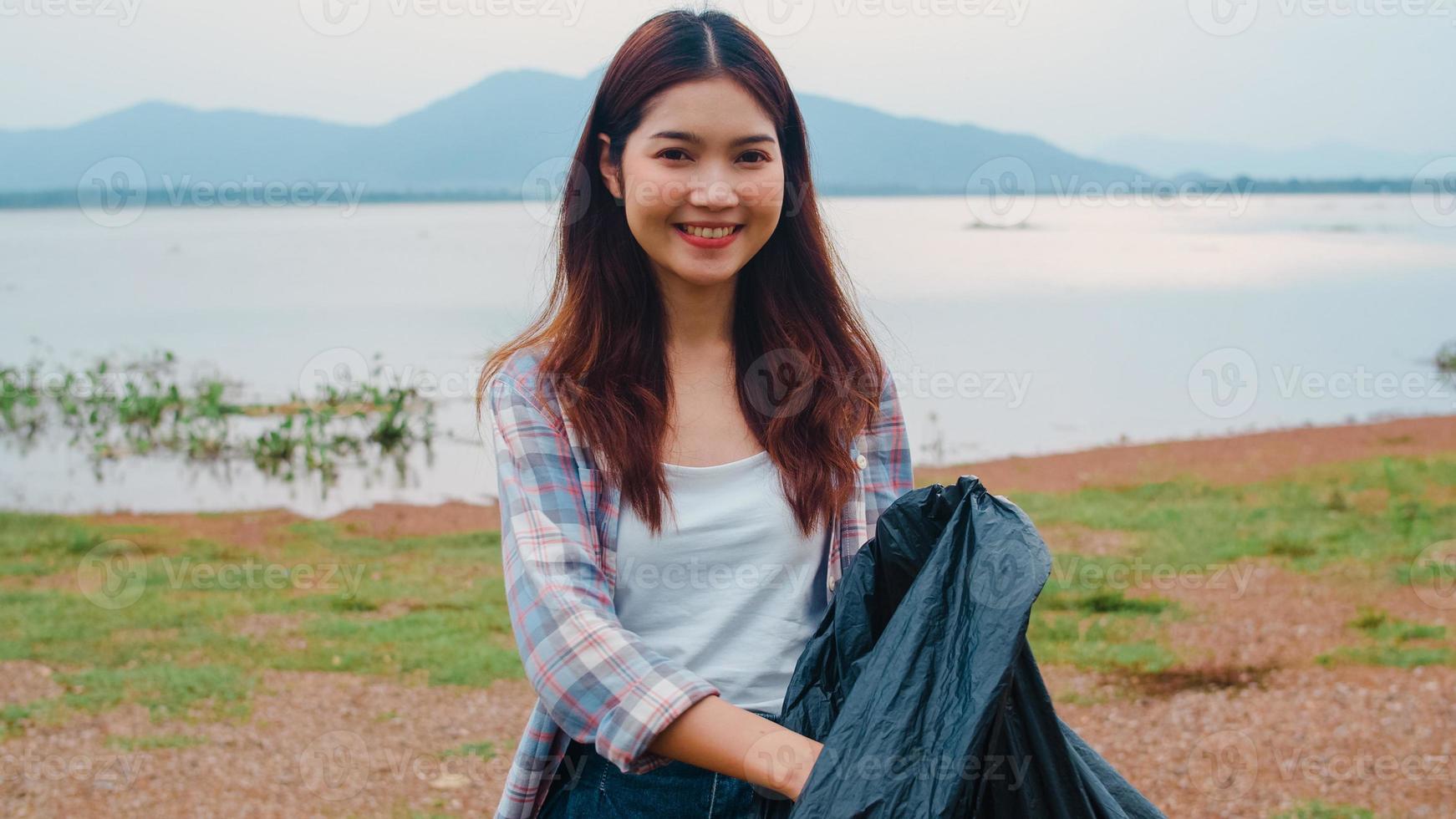 El retrato de una joven dama de Asia que los voluntarios ayudan a mantener la naturaleza limpia sosteniendo botellas de plástico y bolsas de basura negras en la playa. concepto sobre los problemas de contaminación de la conservación del medio ambiente. foto
