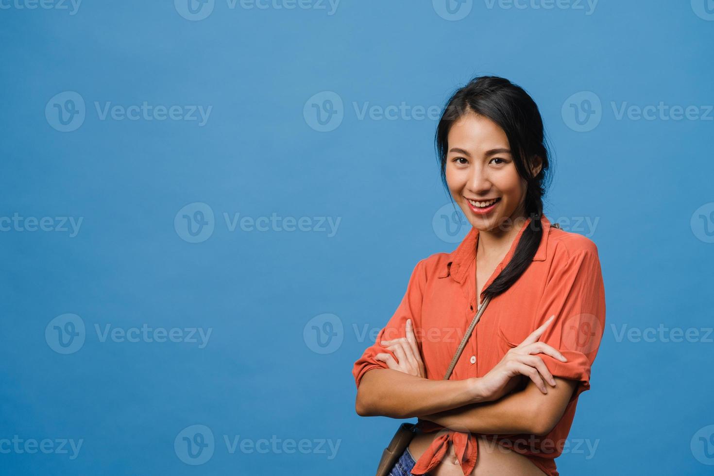 Portrait of young Asia lady with positive expression, arms crossed, smile broadly, dressed in casual clothing and looking at camera over blue background. Happy adorable glad woman rejoices success. photo