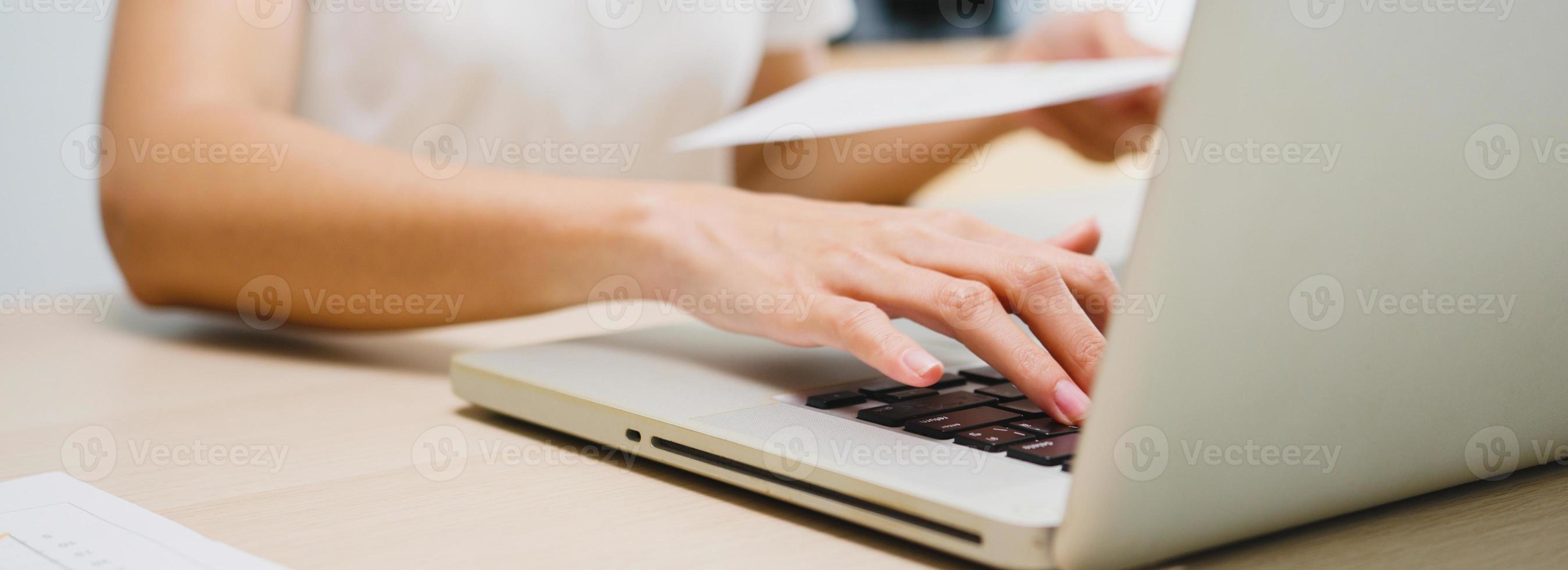 ropa casual de la empresaria independiente de Asia usando la computadora portátil que trabaja en la sala de estar en casa. a distancia, distanciamiento social, cuarentena para la prevención del coronavirus. Fondo de banner panorámico con espacio de copia. foto