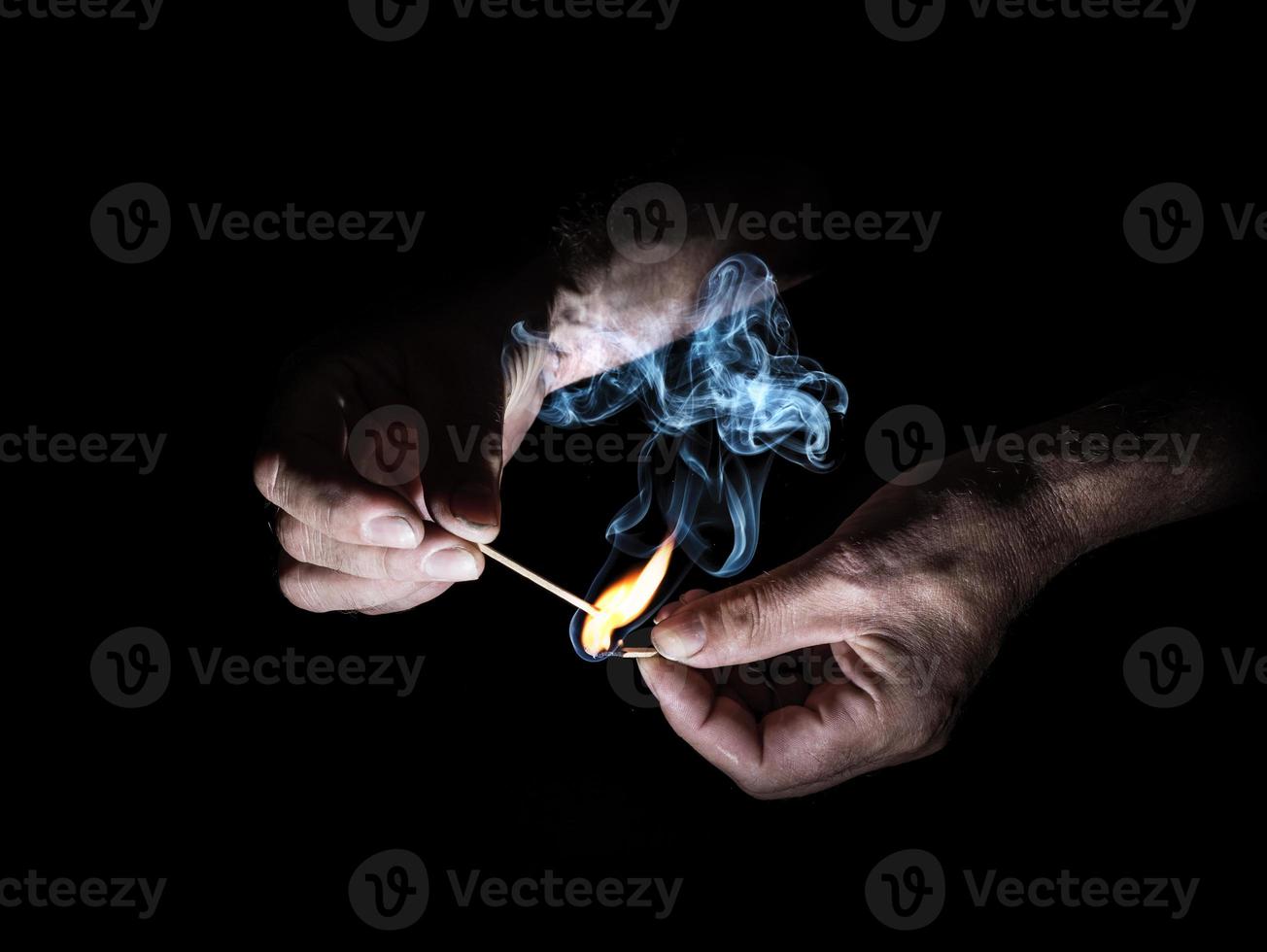 Two hands light a stick wood with a small cloud of smoke photo