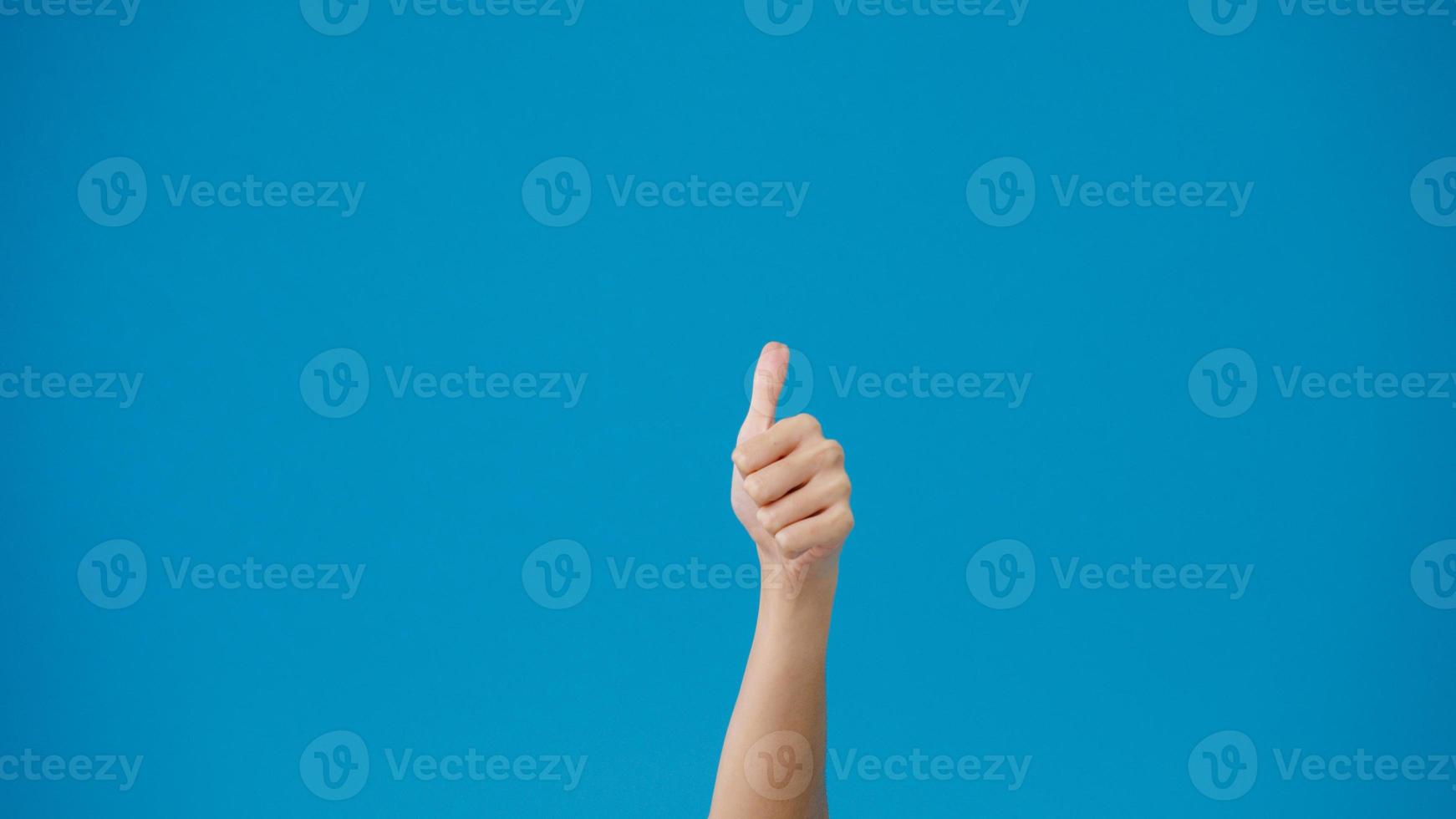 Young woman hand showing thumb up sign with fingers isolated over blue background in studio. Copy space for place a text, message for advertisement. Advertising area, mock up promotional content. photo