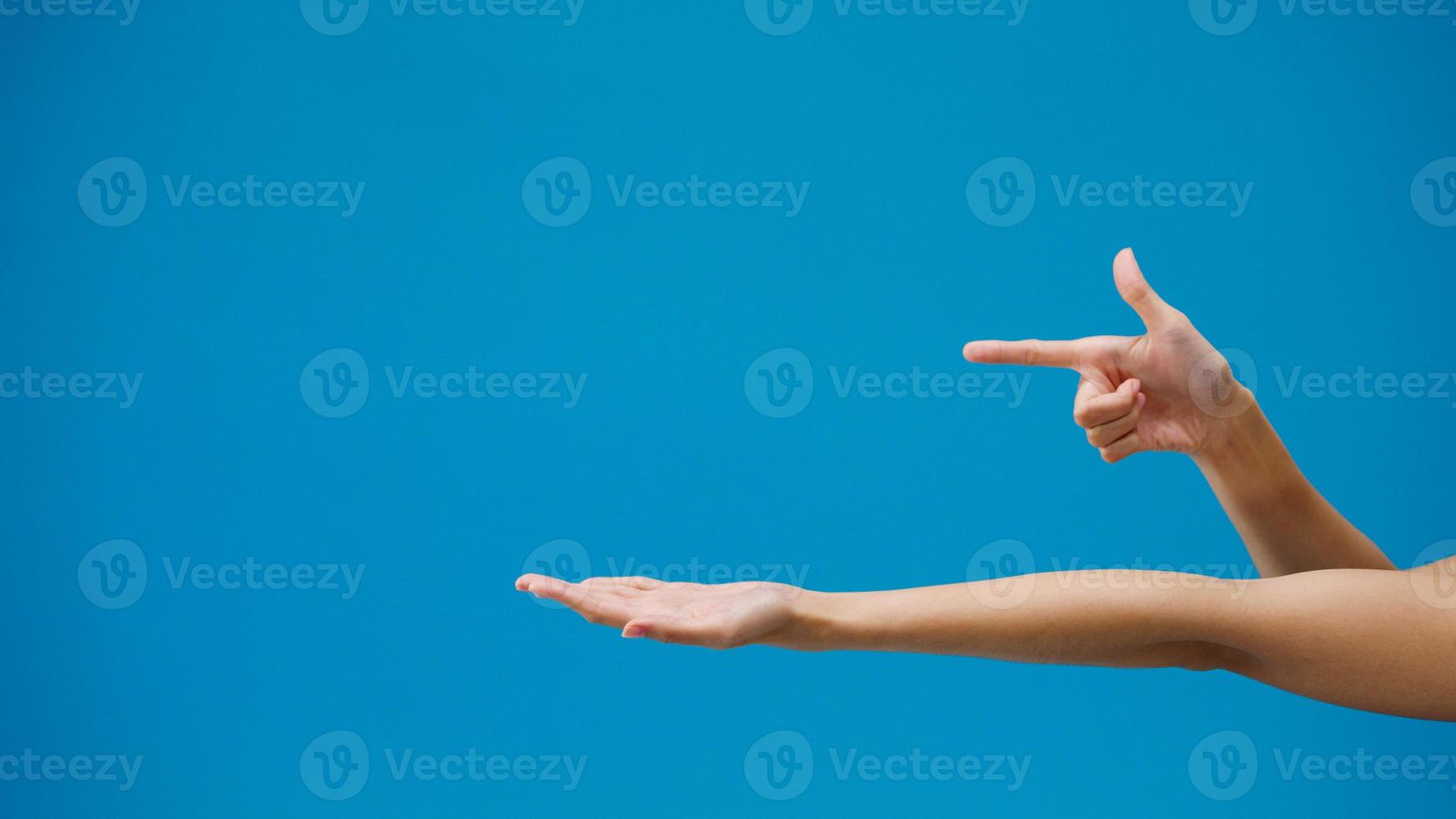 Young girl hand shows something amazing at blank space isolated over blue background in studio. Copy space for place a text, message for advertisement. Advertising area, mock up promotional content. photo