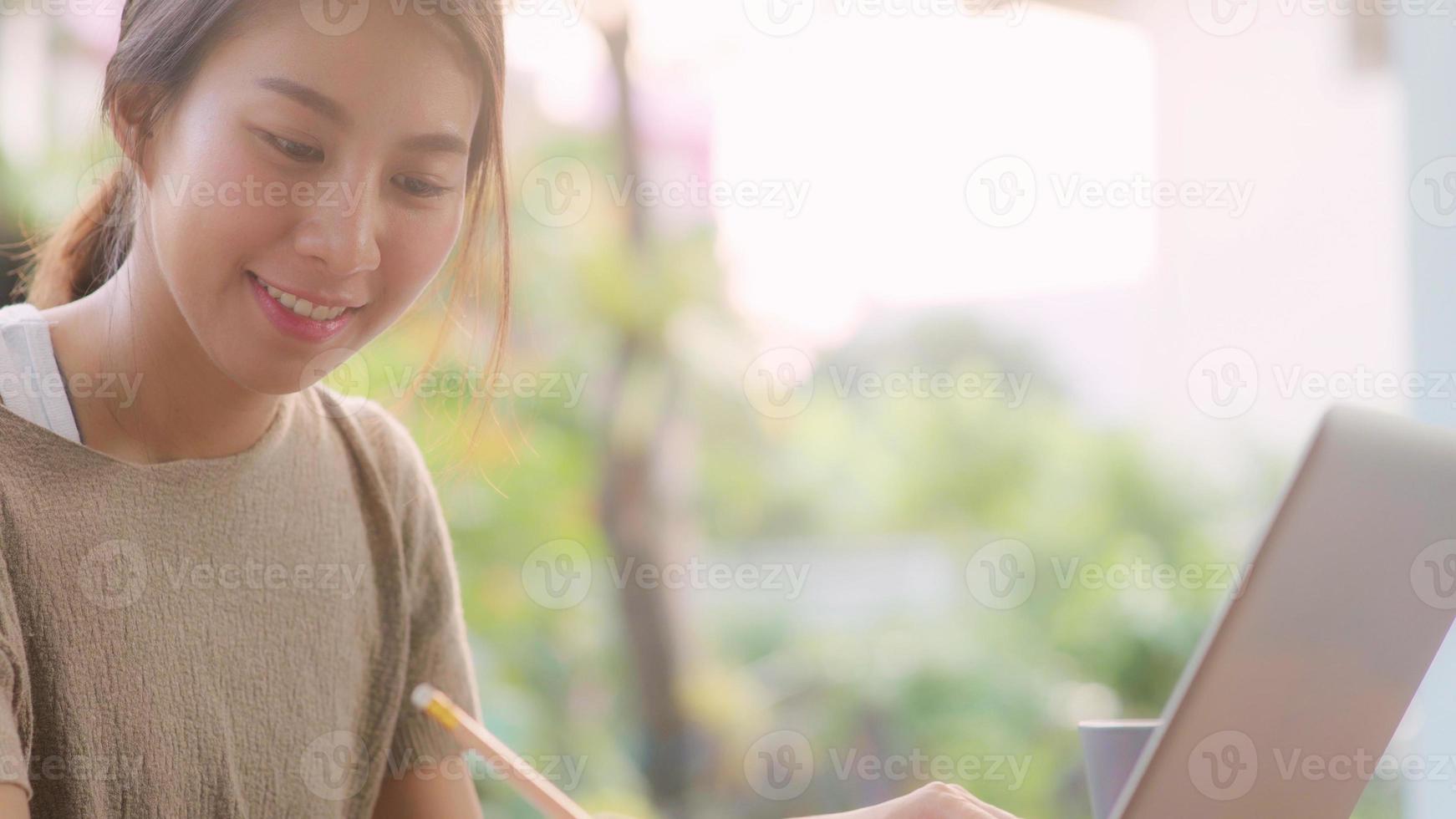 Freelance Asian woman working at home, business female working on laptop sitting on table in the garden in morning. Lifestyle women working at home concept. photo