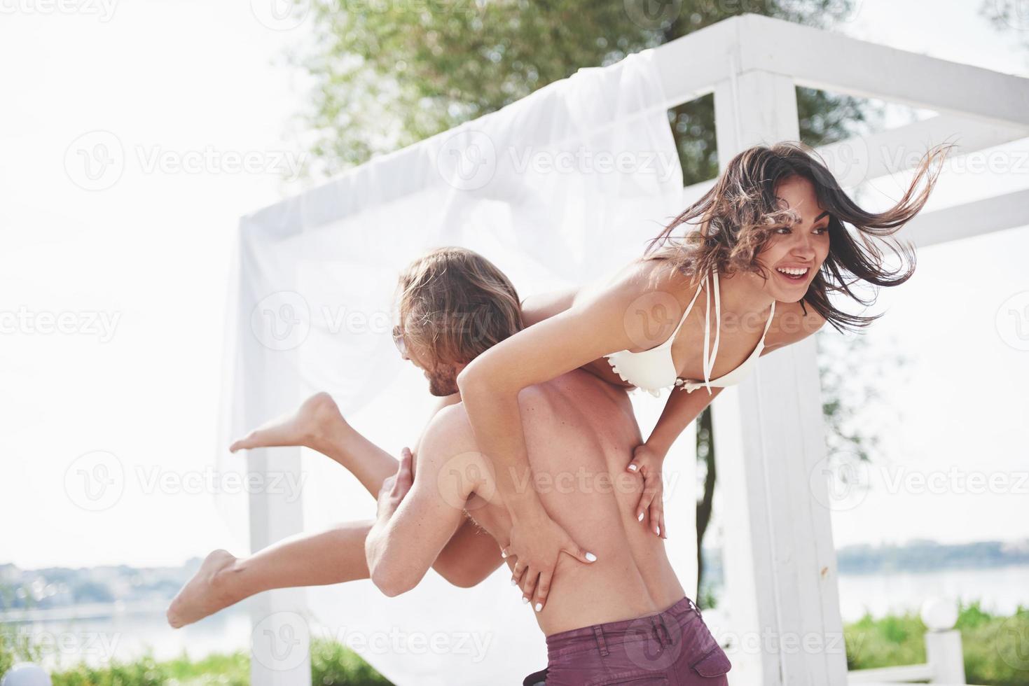 Beautiful young people are fond of it. A man holds a woman on his shoulders, they are playful and romantic. photo