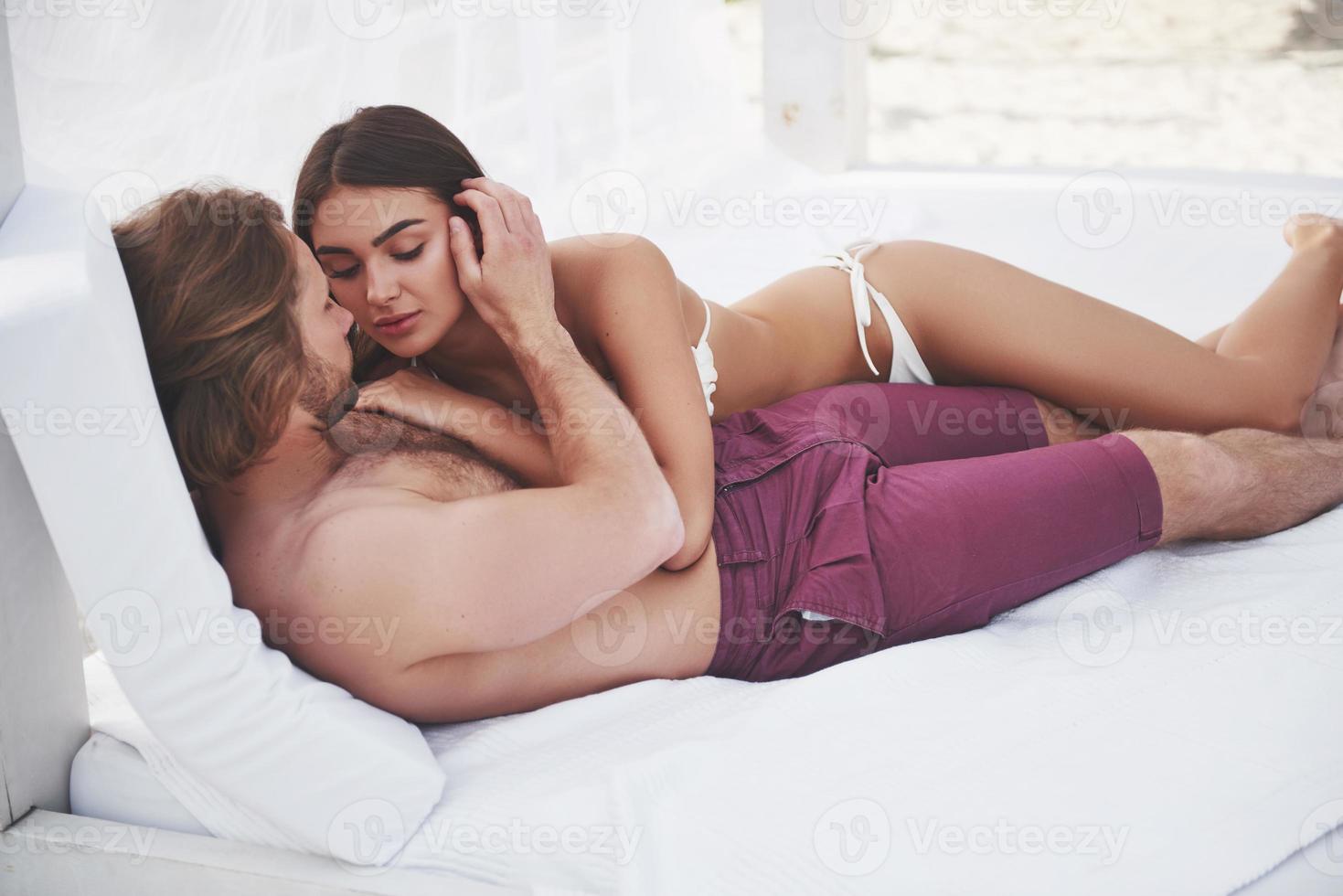 Beautiful young couple in swimsuits on the beach against a sand smile and hug. photo