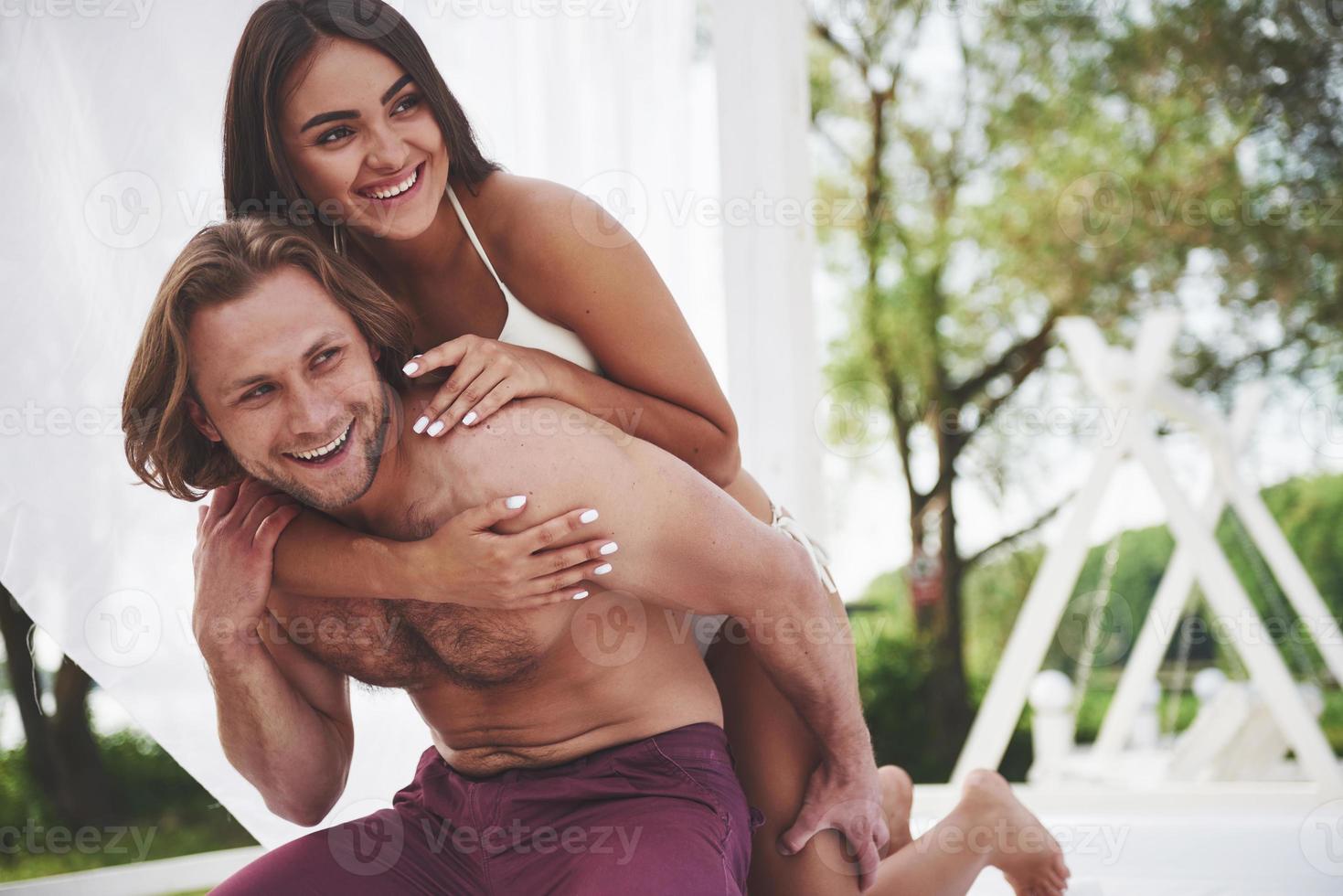 A beautiful couple relaxing on the sandy beach, wearing bathing clothes. Romantic atmosphere photo