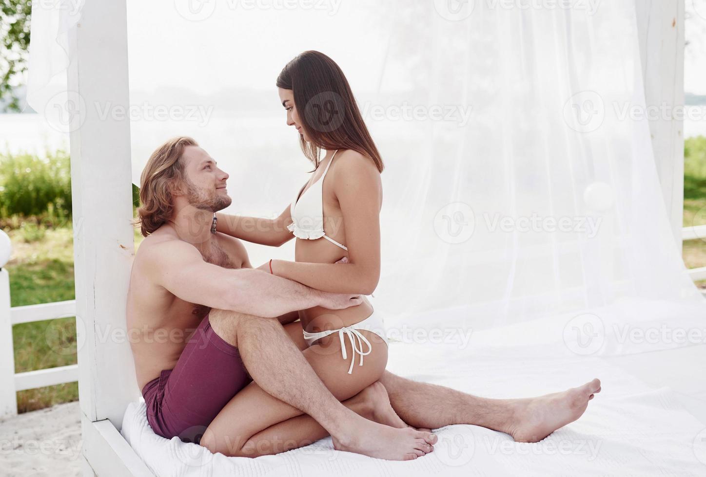 una hermosa pareja relajándose en la playa de arena, vistiendo ropa de baño. ambiente romantico foto