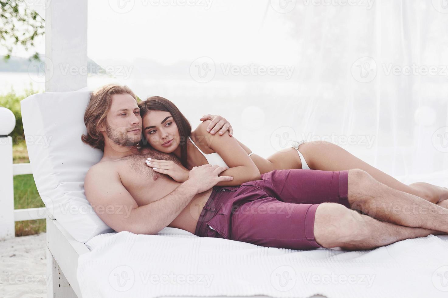 A beautiful couple relaxing on the sandy beach, wearing bathing clothes. Romantic atmosphere. photo