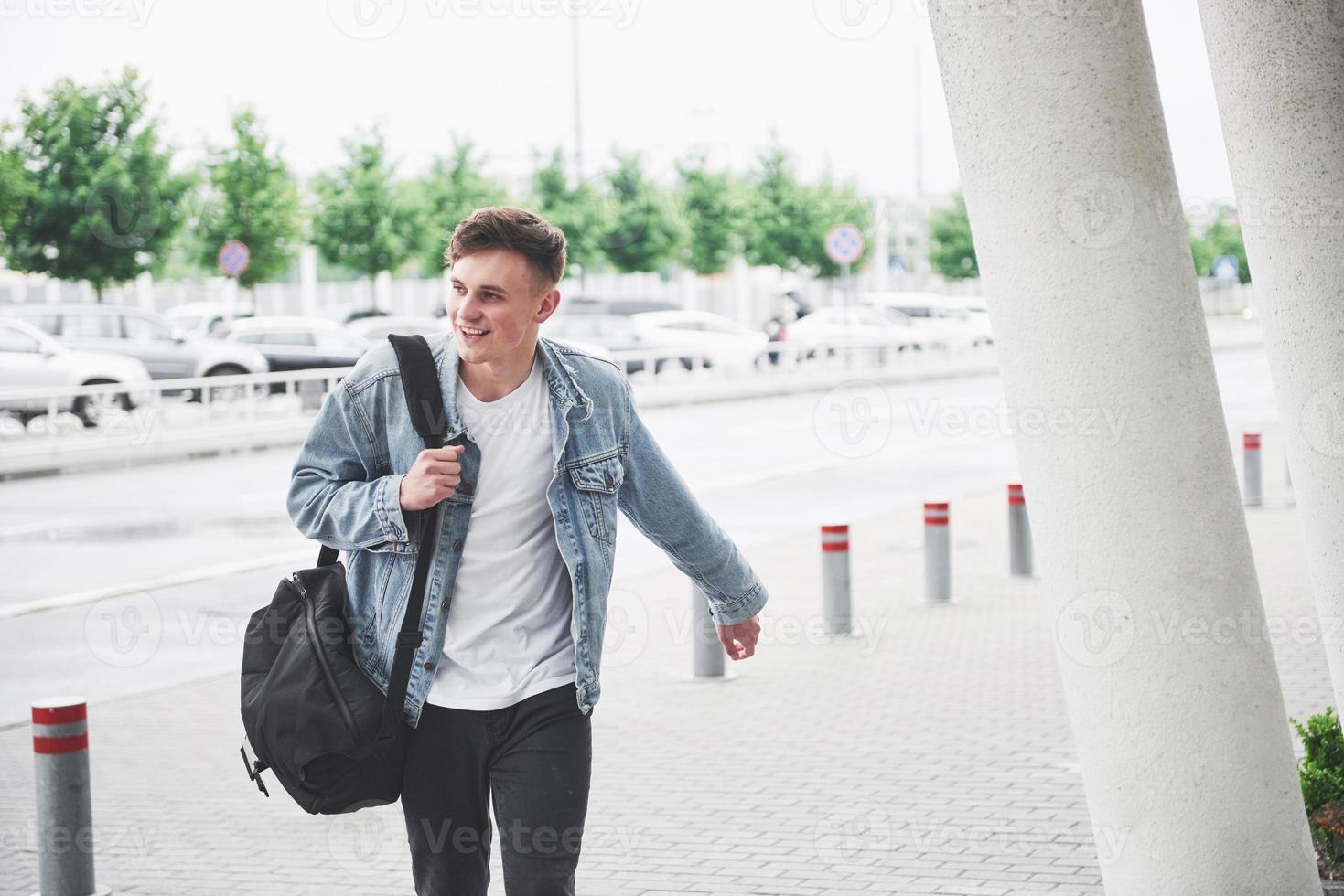 Young handsome man with a bag on his shoulder in a hurry to the airport. photo