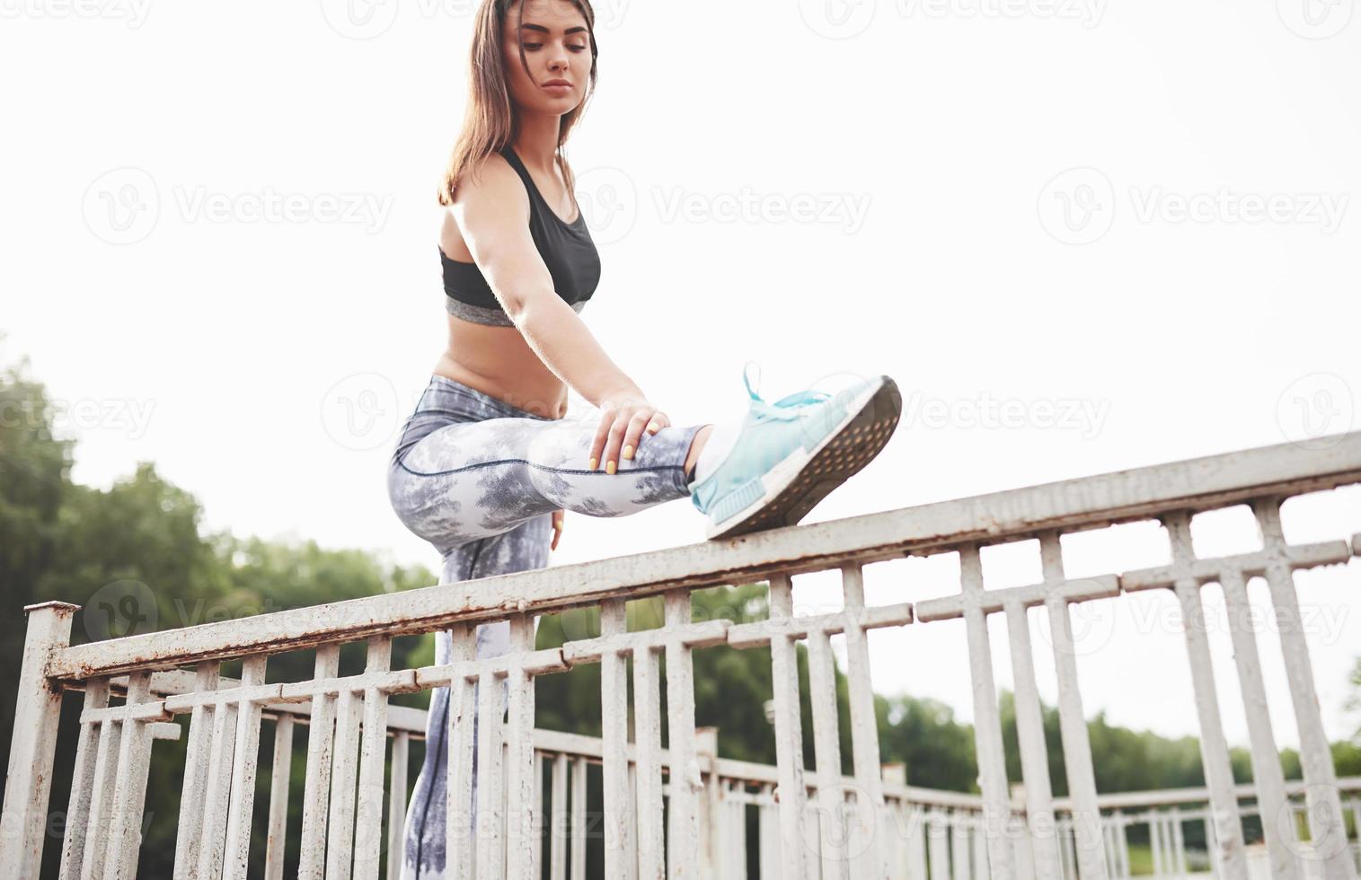 A beautiful athlete brunette performs outdoor exercises photo