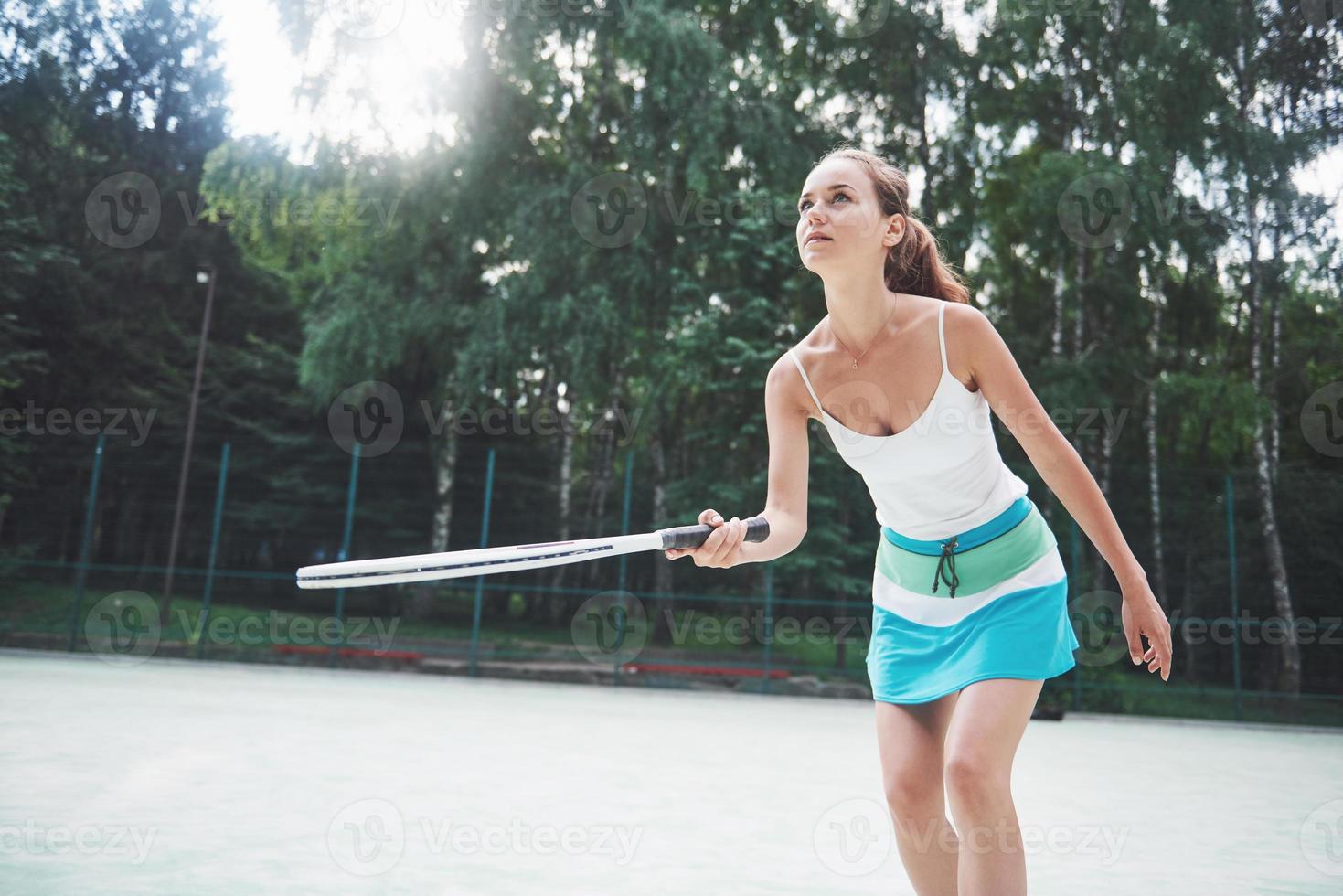 Woman in sportswear serves tennis ball. photo