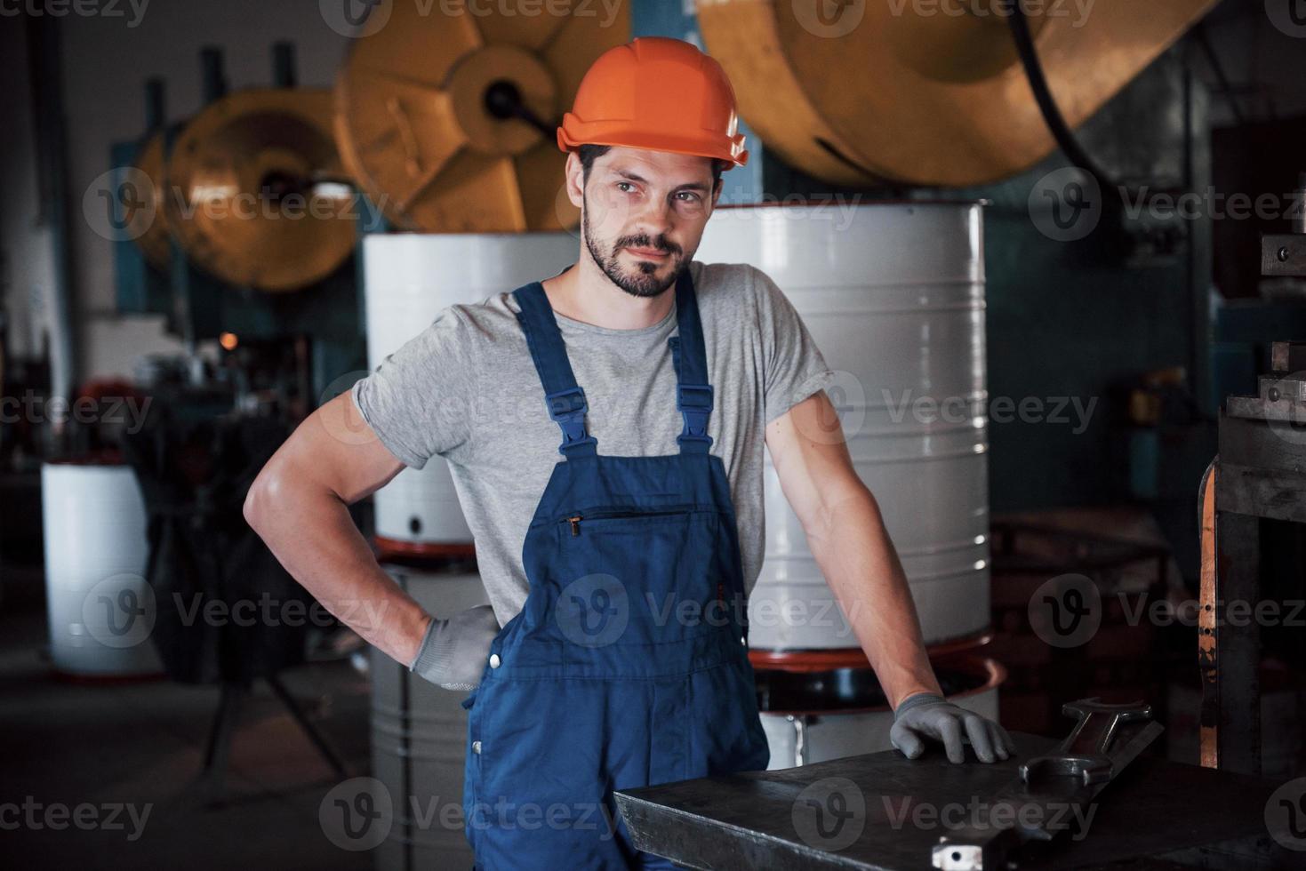 retrato de un joven trabajador con casco en una gran fábrica de reciclaje de residuos. el ingeniero supervisa el trabajo de las máquinas y otros equipos foto