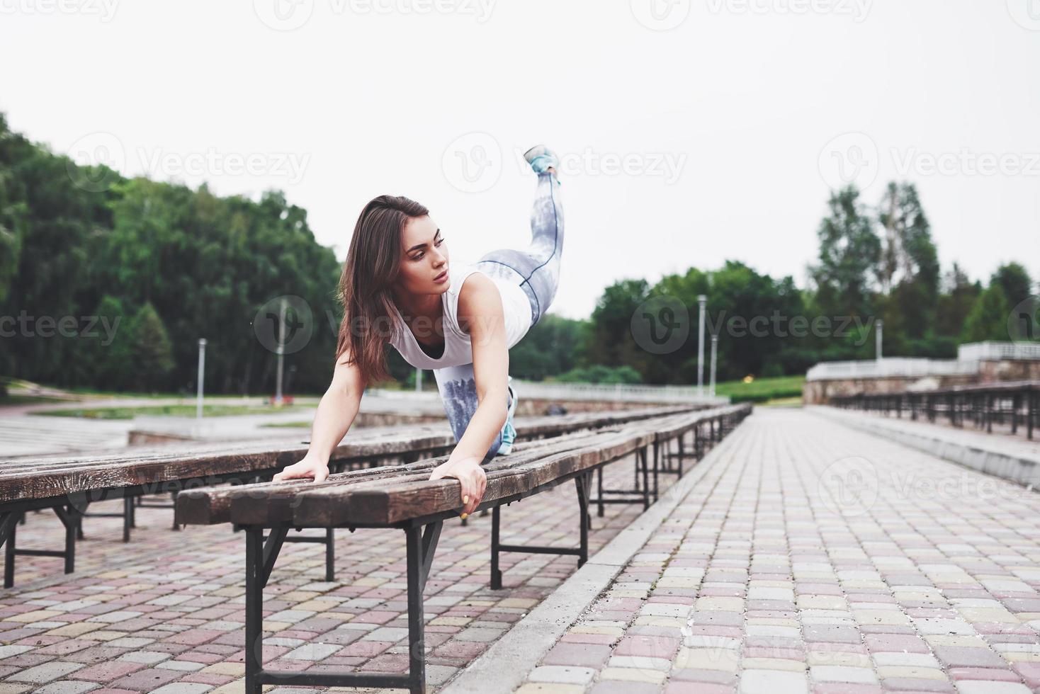 A beautiful athlete brunette performs outdoor exercises photo