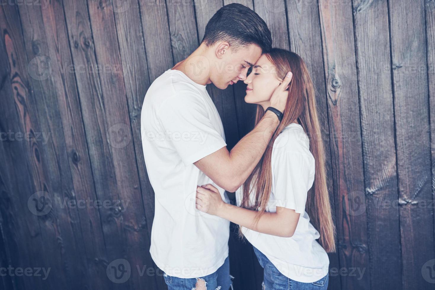 Young couple, guy and girl together on a wooden wall background. They are happy together and dressed alike. Always in a trend photo