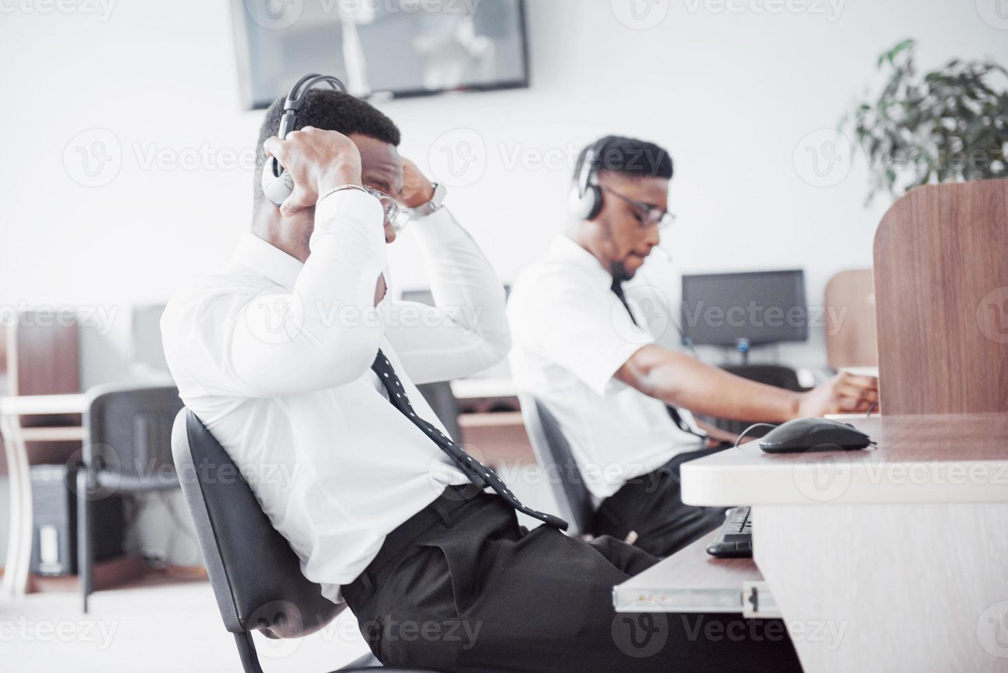 Operador de soporte al cliente afroamericano con auriculares manos libres trabajando en la oficina foto