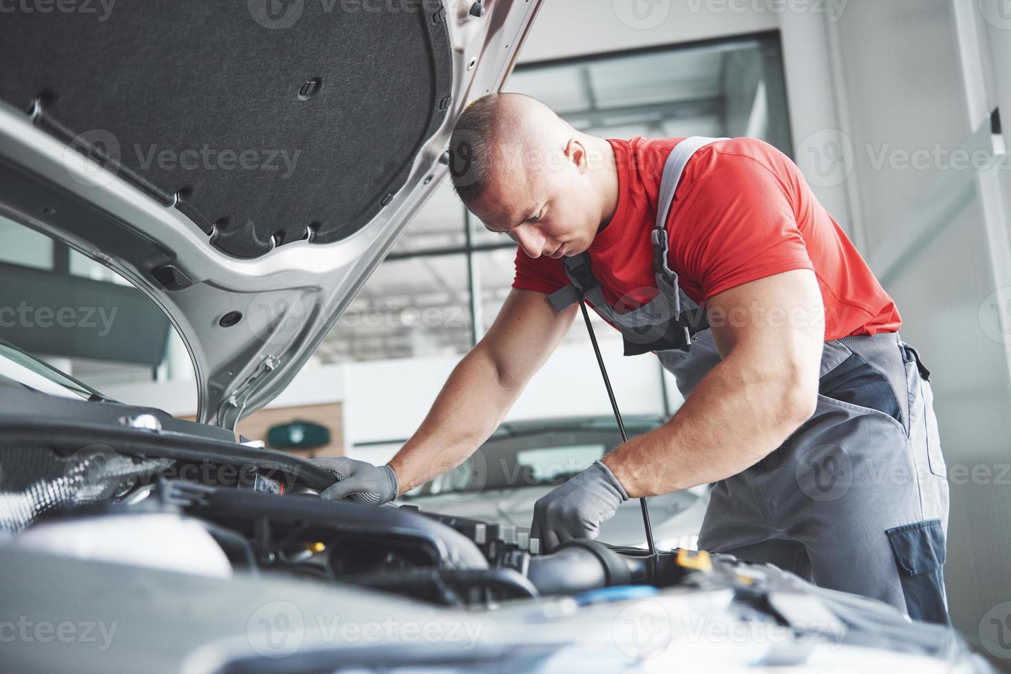 Imagen que muestra un trabajador de servicio de coche musculoso reparando el vehículo foto