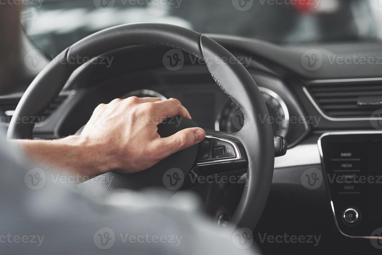 Man's big hands on a steering wheel while driving a car. photo