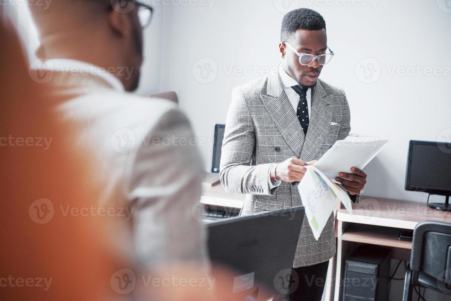 Modern businessman at work. Two confident business people in formalwear discussing something While one of them looks at the documents and the second an important phone call photo