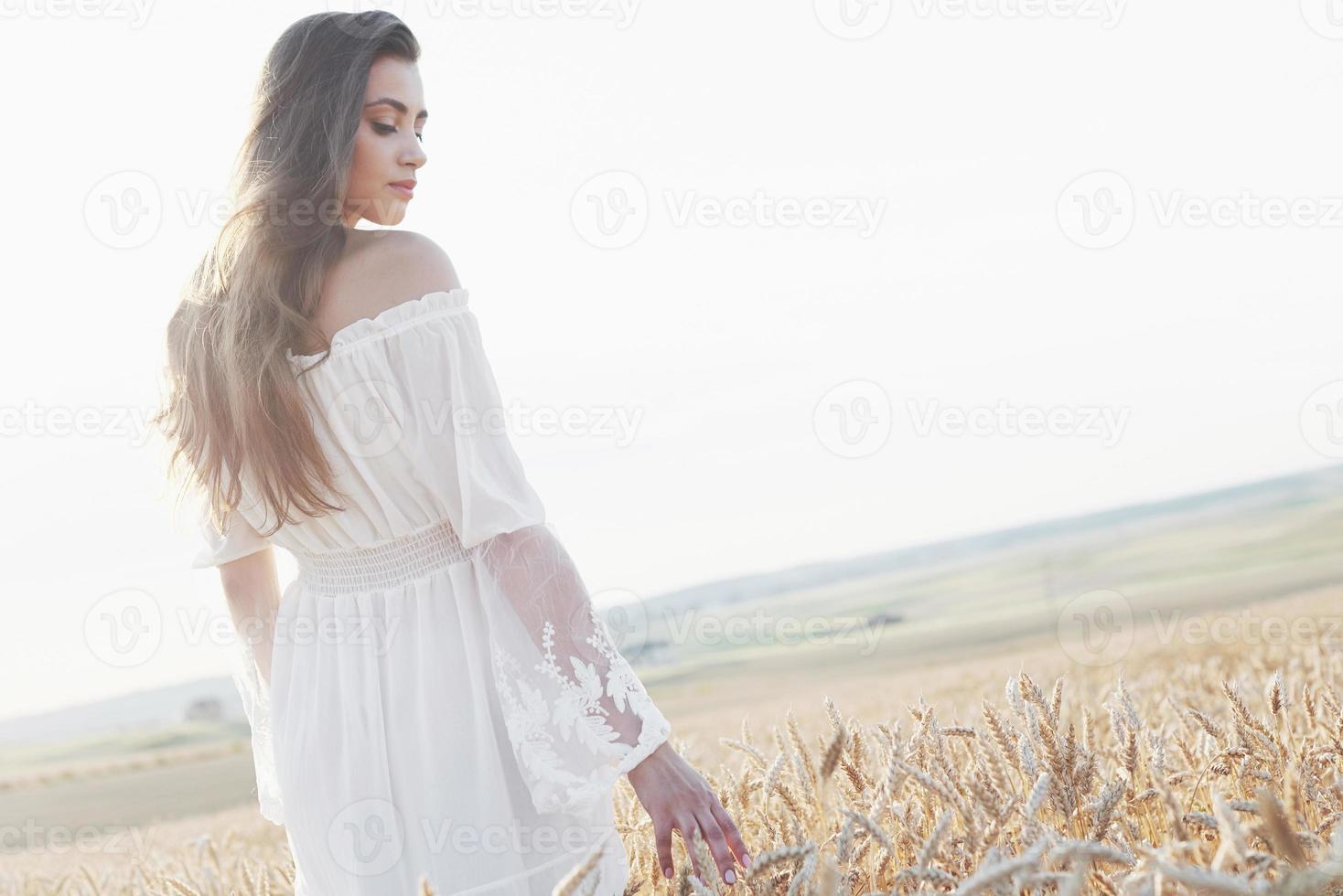 Beautiful girl in white dress running on the autumn field of wheat at sunset time photo