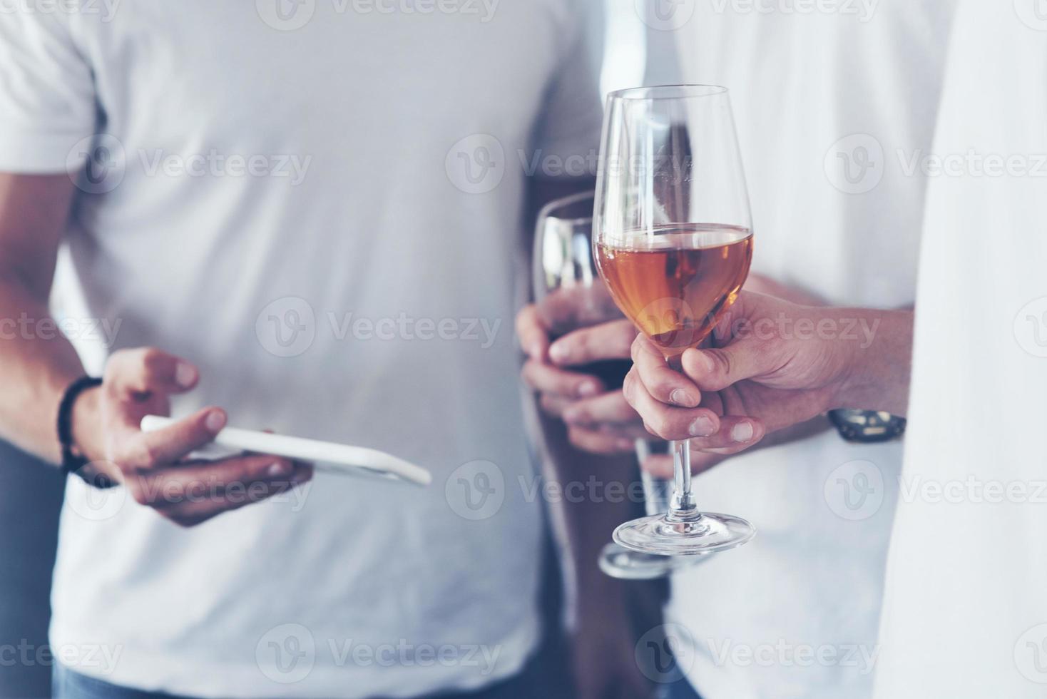 Cheerful old friends communicate with each other and phone watch, with glasses of whiskey or wine in pub. Concept of entertainment and lifestyle. Wifi connected people in bar table meeting photo