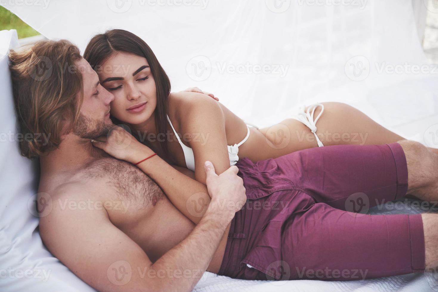Beautiful young couple in swimsuits on the beach against a sand smile and hug. photo