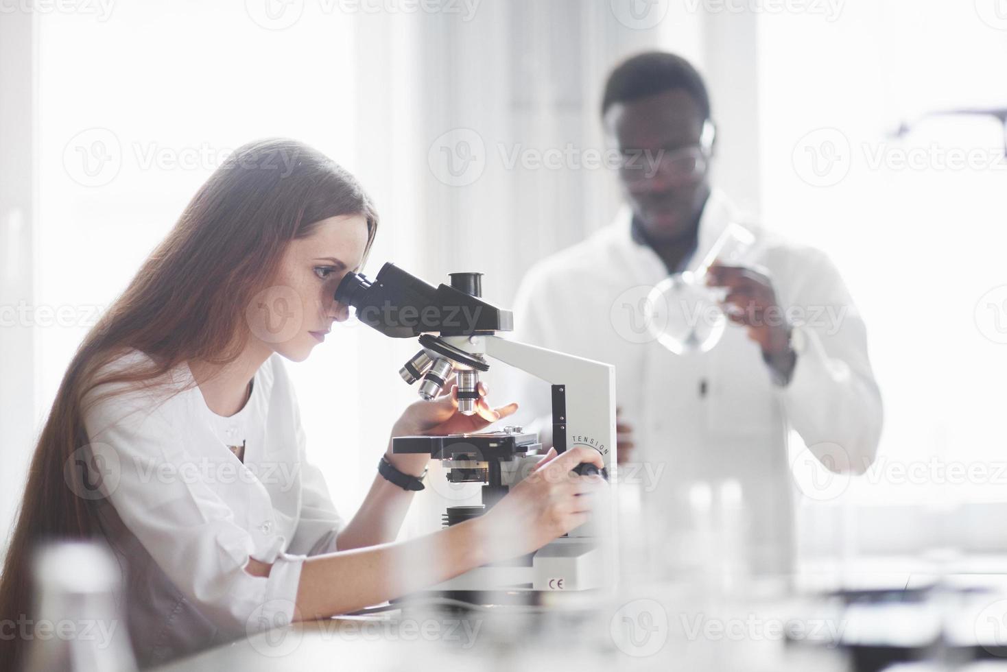 asistente de laboratorio con microscopio bombilla de cristalería de laboratorio con productos químicos. foto