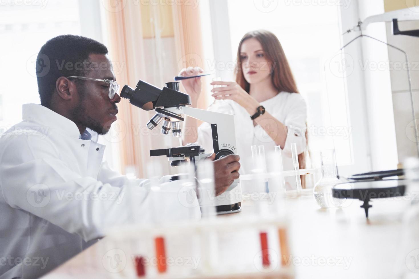 The scientist works with a microscope in a laboratory conducting experiments and formulas. photo