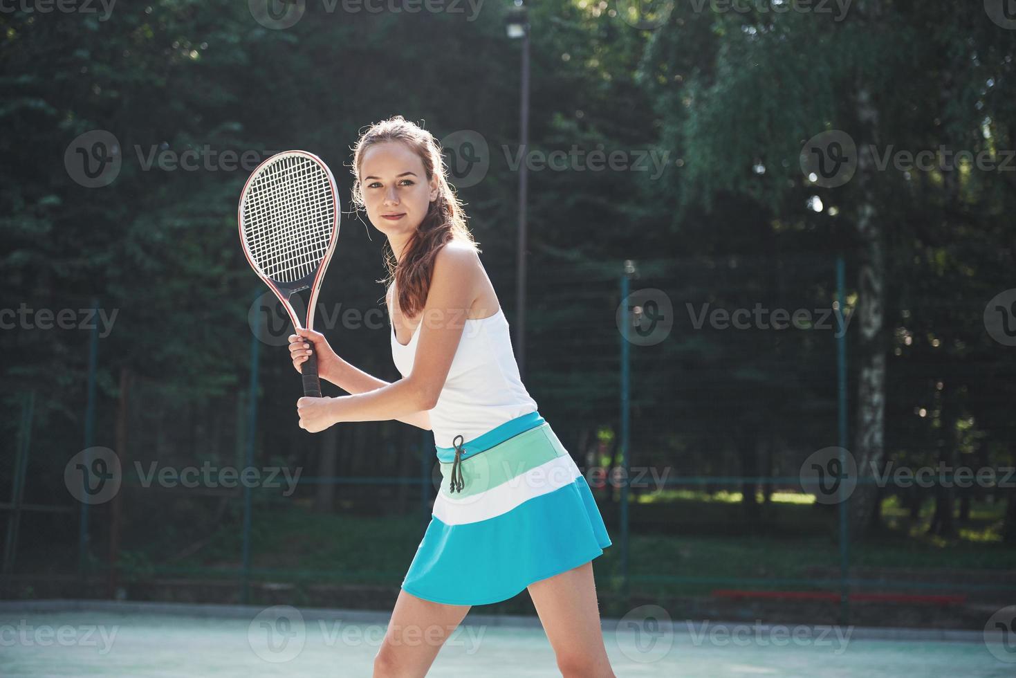 Una mujer bonita vistiendo una cancha de tenis de ropa deportiva en la cancha foto